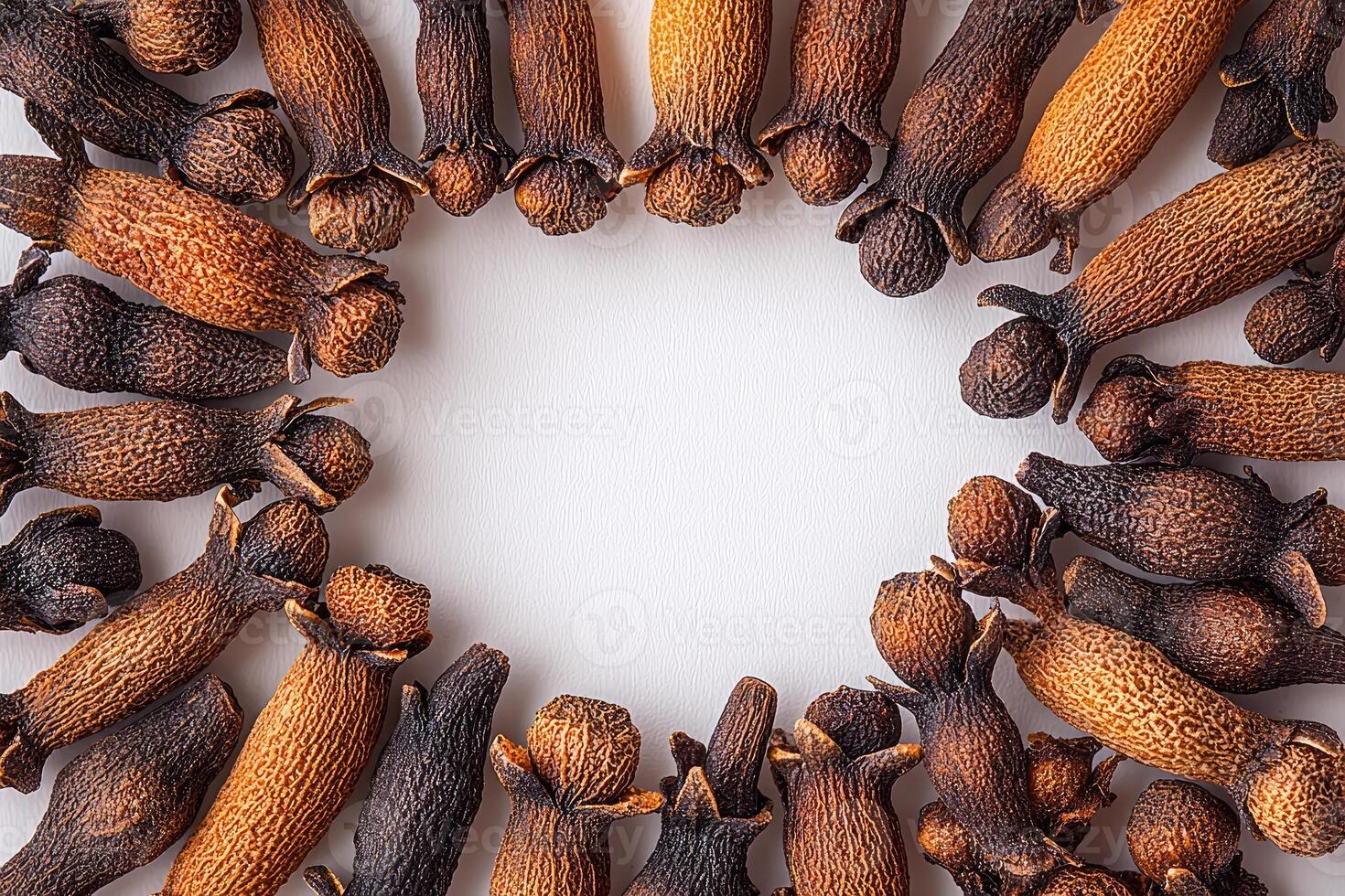 Dried clove spices arranged in a circular pattern on a white surface photo