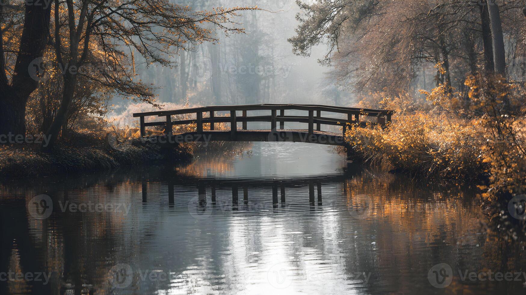 A serene wooden bridge spans the tranquil river reflecting autumn trees in the morning light photo