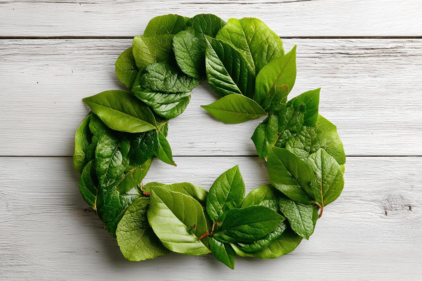 Fresh green leaves neatly arranged in a circular formation on a rustic wooden table symbolize nature and sustainability efforts photo