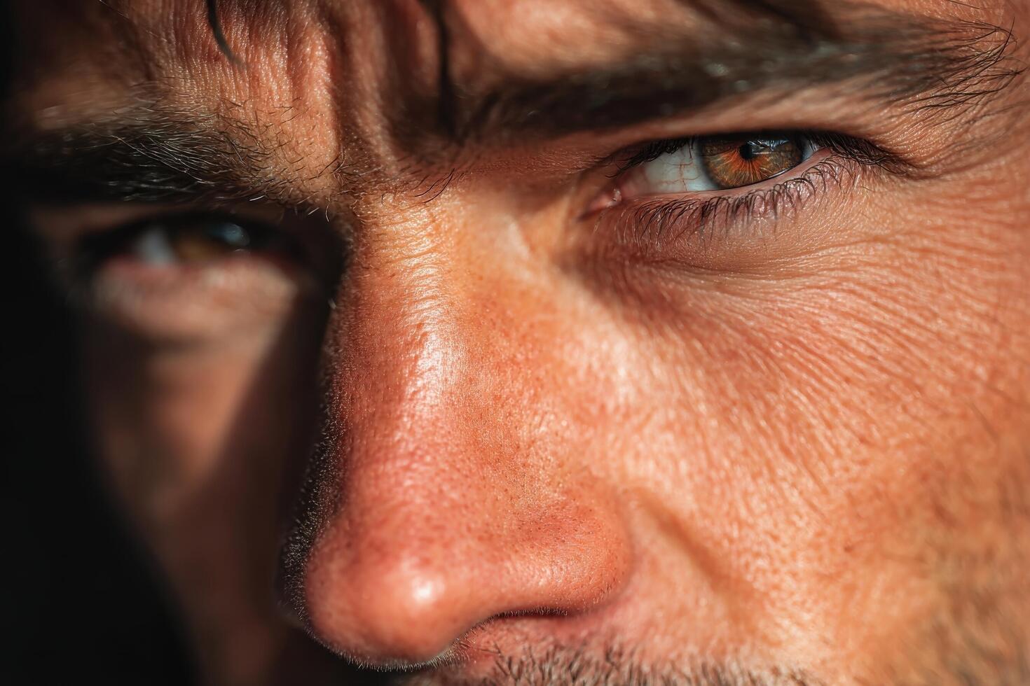 A man stands in strong daylight, his face reflecting character and depth with expressive eyes that draw attention to his features photo