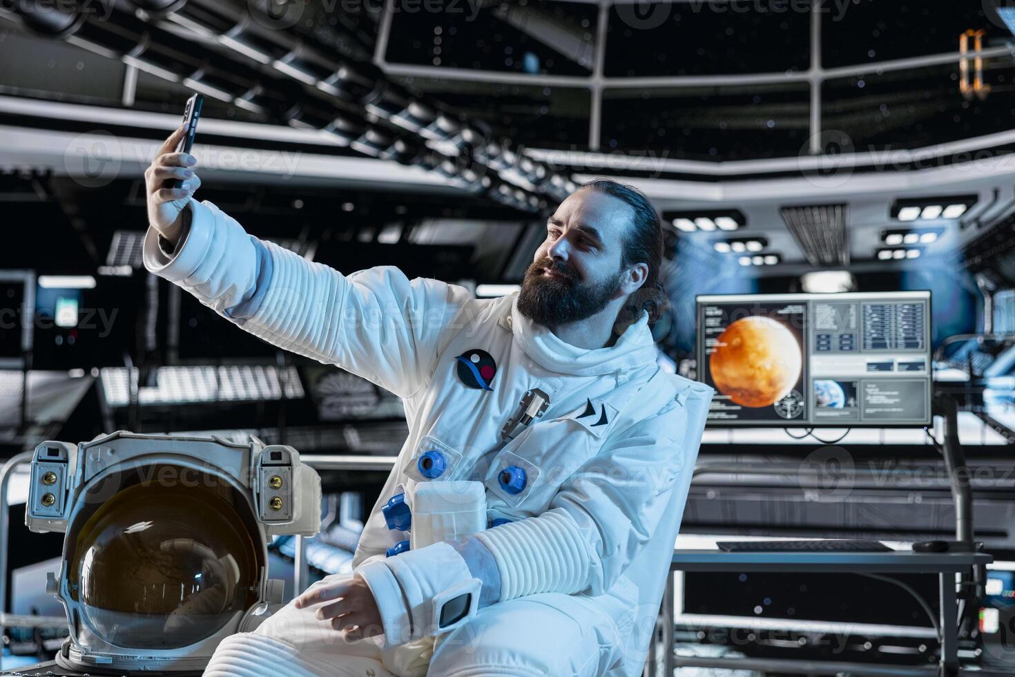 Astronaut wearing spacesuit inside futuristic spacecraft doing selfie with smartphone. Smiling spaceman wearing equipment doing photos with mobile phone during space travel operations