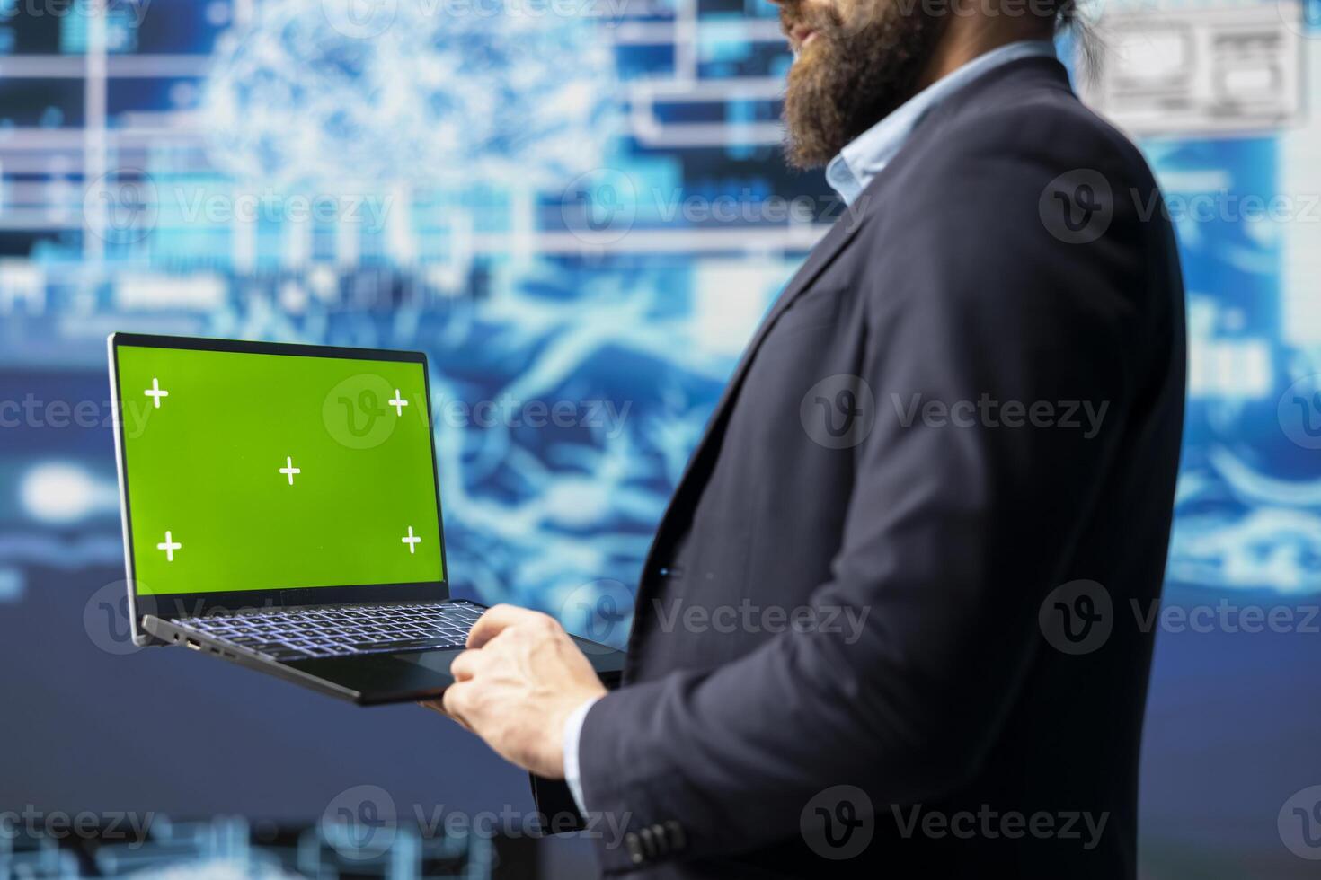 Surrounded by data and neural networks systems, male IT engineer navigates artificial intelligence with a chroma key on laptop. Using automation for modern strategy and innovation. photo