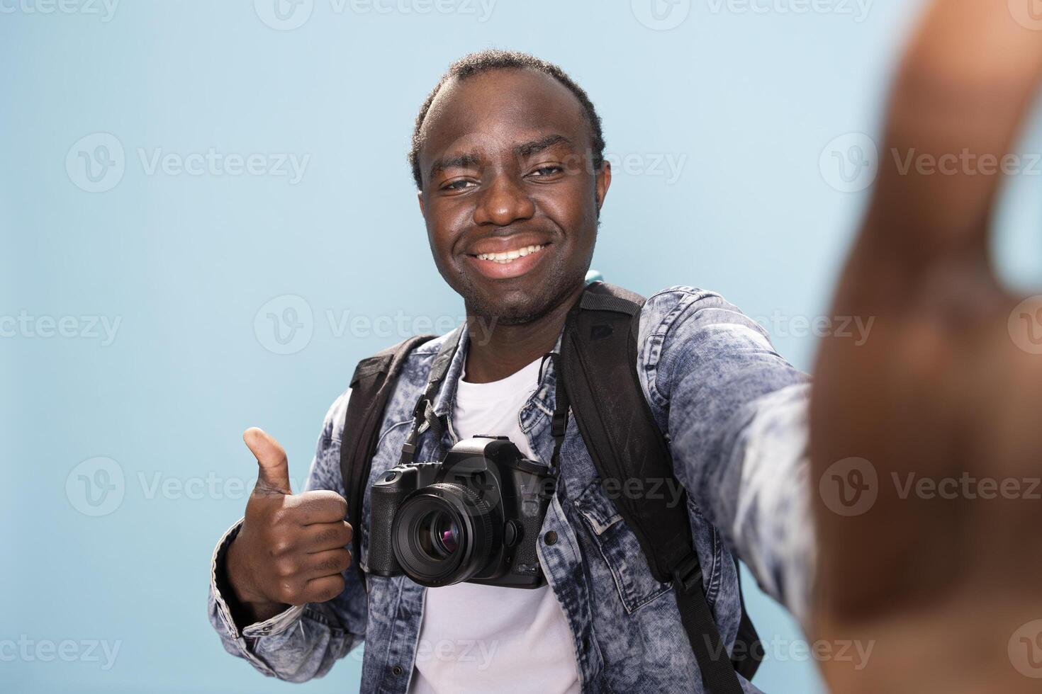 African american male vlogger giving thumbs up to his online audience, recording himself in studio. Pov of cheerful black photographer making an agreement gesture towards the camera. photo