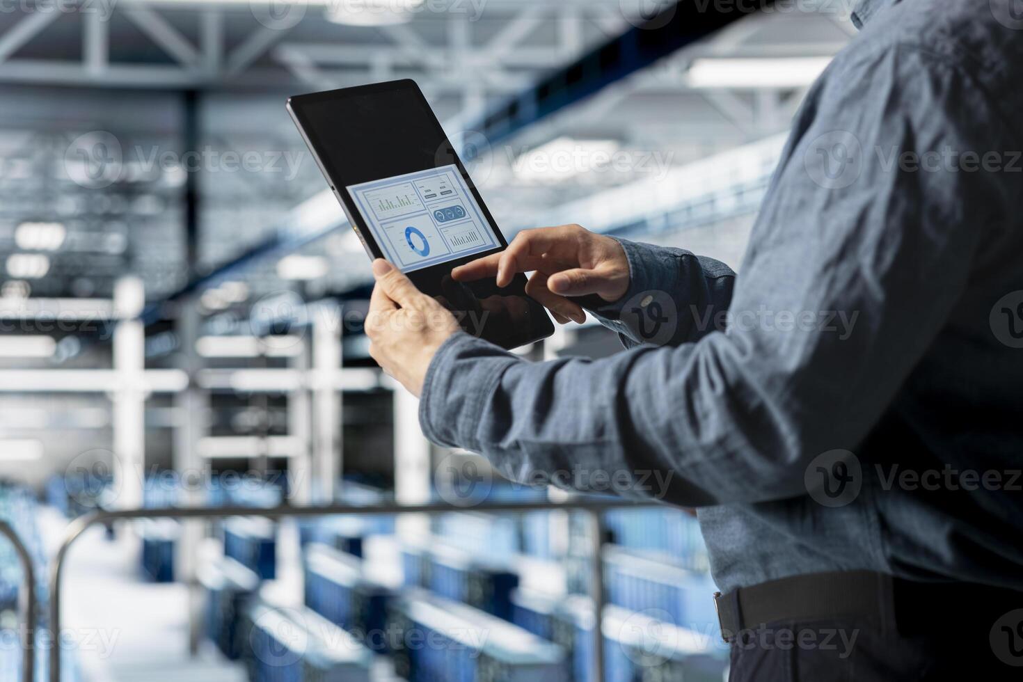 Close up of server room employee analyzing equipment metrics on device screen. Data center engineer looking at analysis charts on tablet from data gathered by infrastructure rigs photo