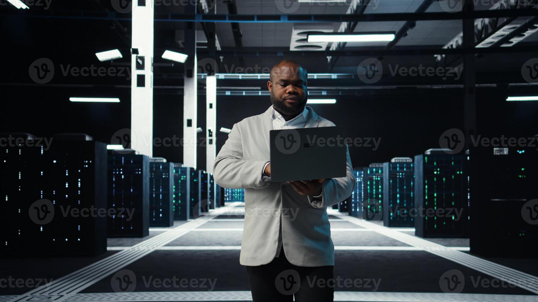 Data center system administrator coding on laptop, doing software updates. Server room IT specialist looking at device screen, optimizing infrastructure rackmounts configuration rigs, camera A photo