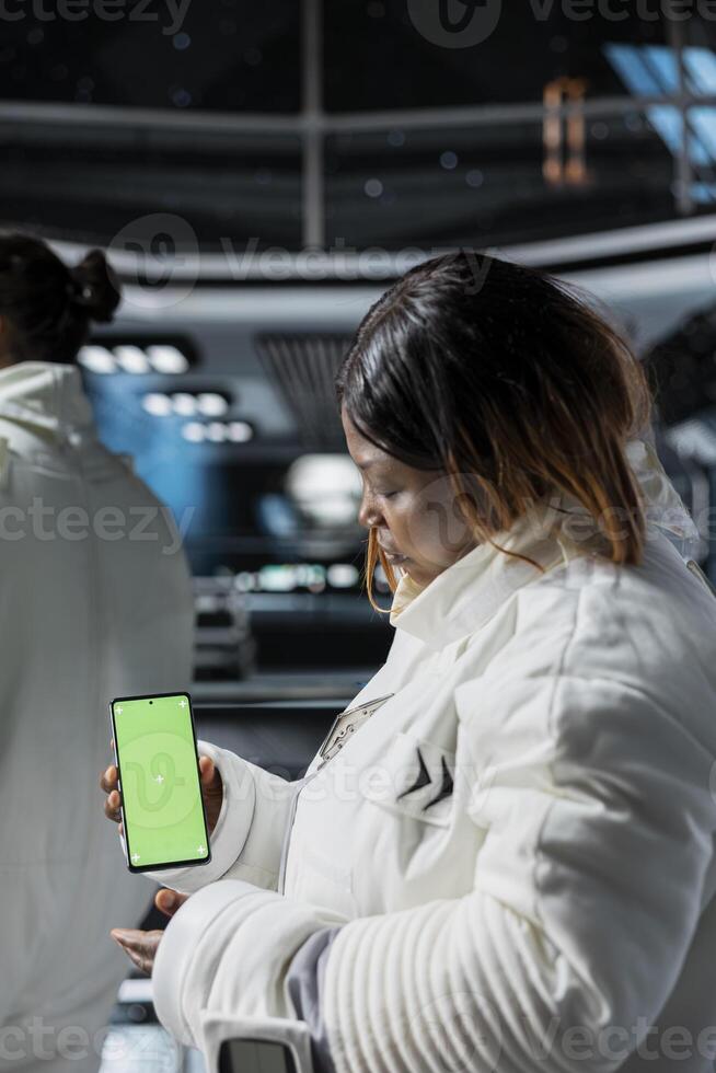 Astronauts doing tests using mockup smartphone aboard high tech starship during spaceflight. Space station crew members using green screen mobile phone to do systems analysis photo