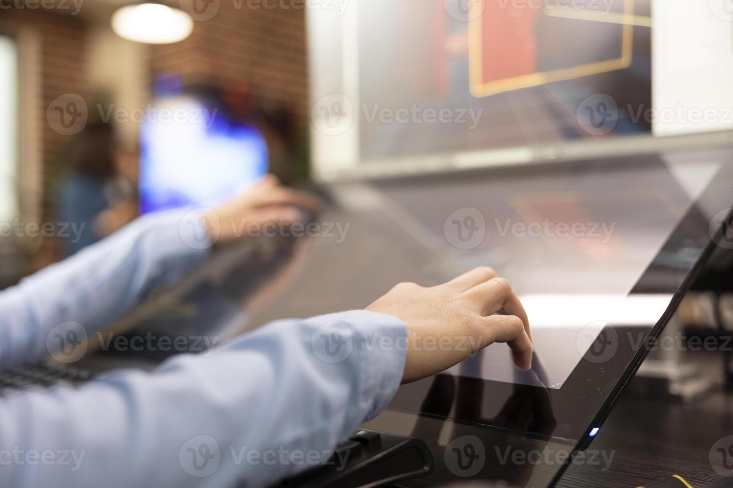 Closeup of creative professional using touchscreen monitor on their office desk, developing 3d videogame scenes. Selective focus on hands of graphic expert utilizing digital screen for illustrations. photo