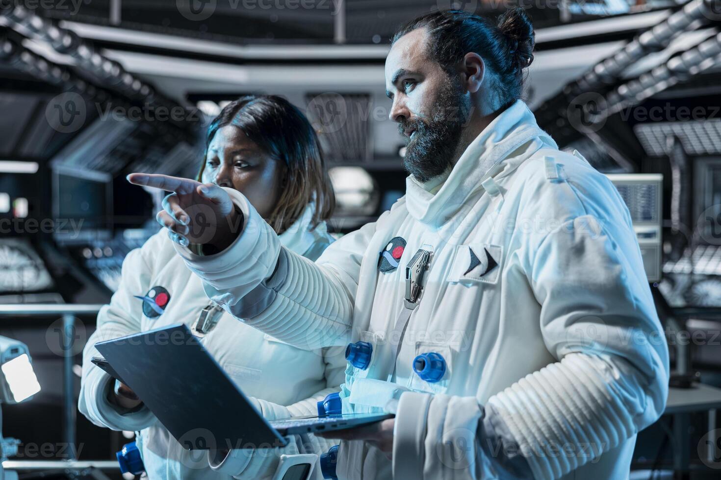 Team of astronauts working together to confirm suit integrity using laptop. Orbital station coworkers chatting, testing gear during routine equipment check using notebook photo