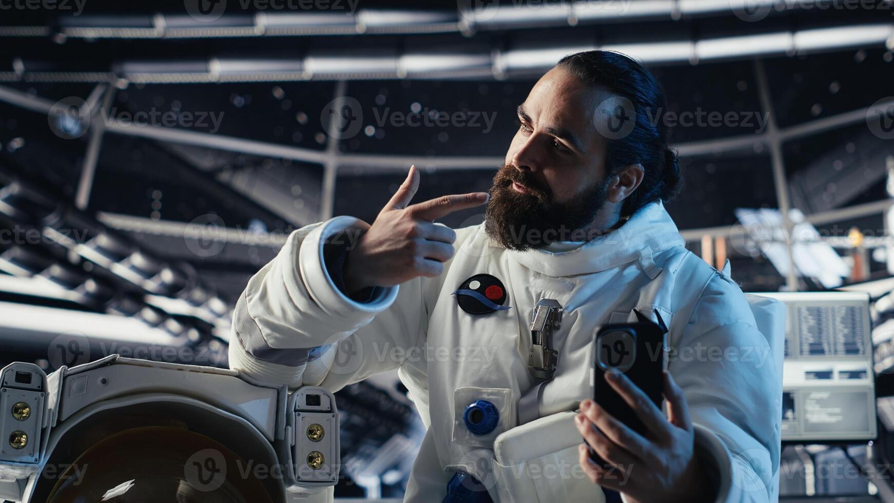 Astronaut records selfie with smartphone, making hand gestures, speaking to subscribers during Mars mission. Cosmonaut recording cosmic exploration content for followers photo