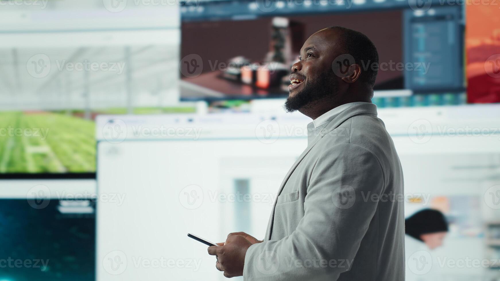 Smiling man using mobile phone surrounded by recommendations while browsing streaming services. Jolly african american man enjoys free time browsing favorite online clips on smartphone, camera A photo