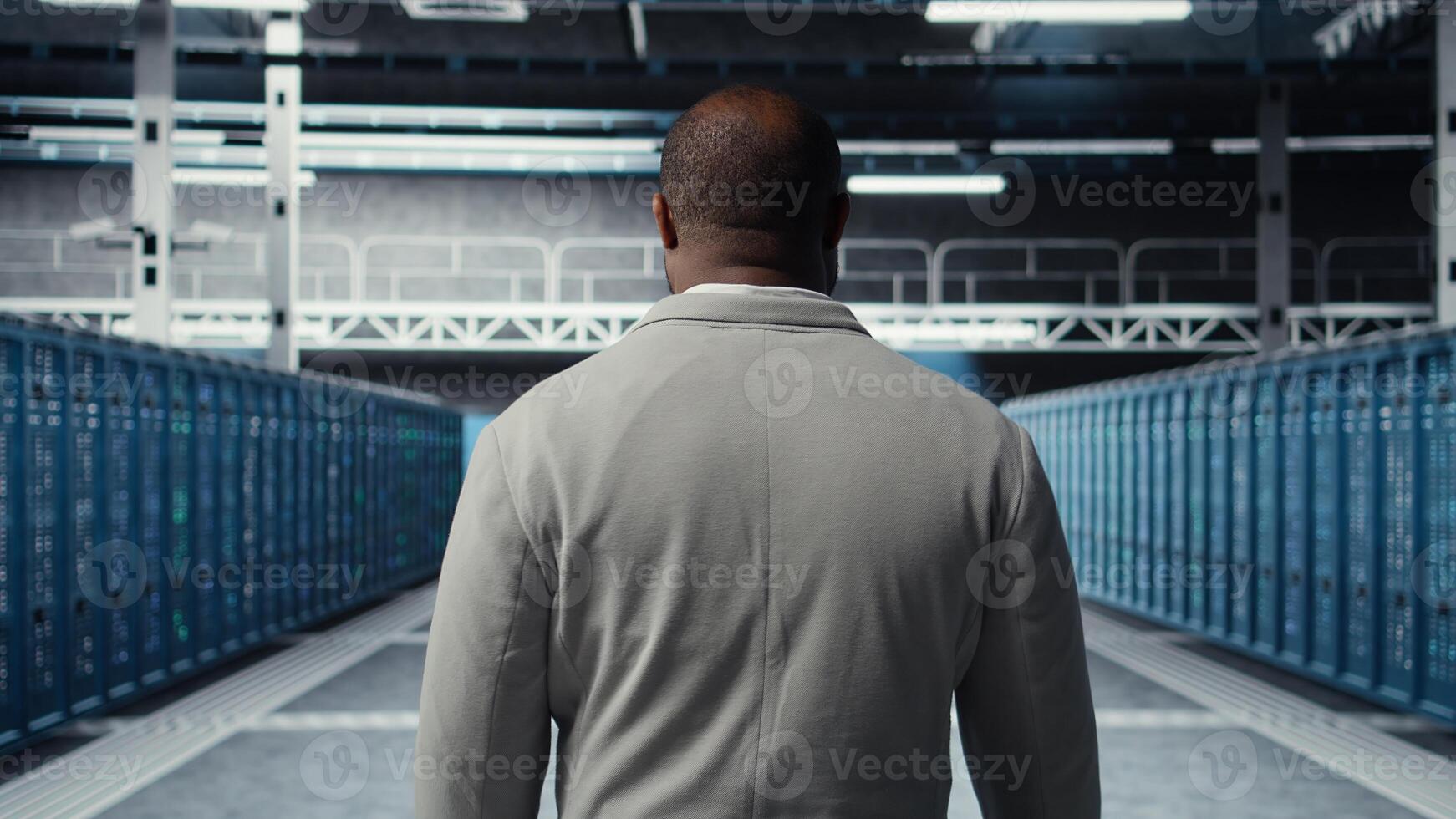 System administrator in data center doing inspection on infrastructure tech handling user requests. African american worker in server farm analyzing traffic patterns of equipment, camera A photo