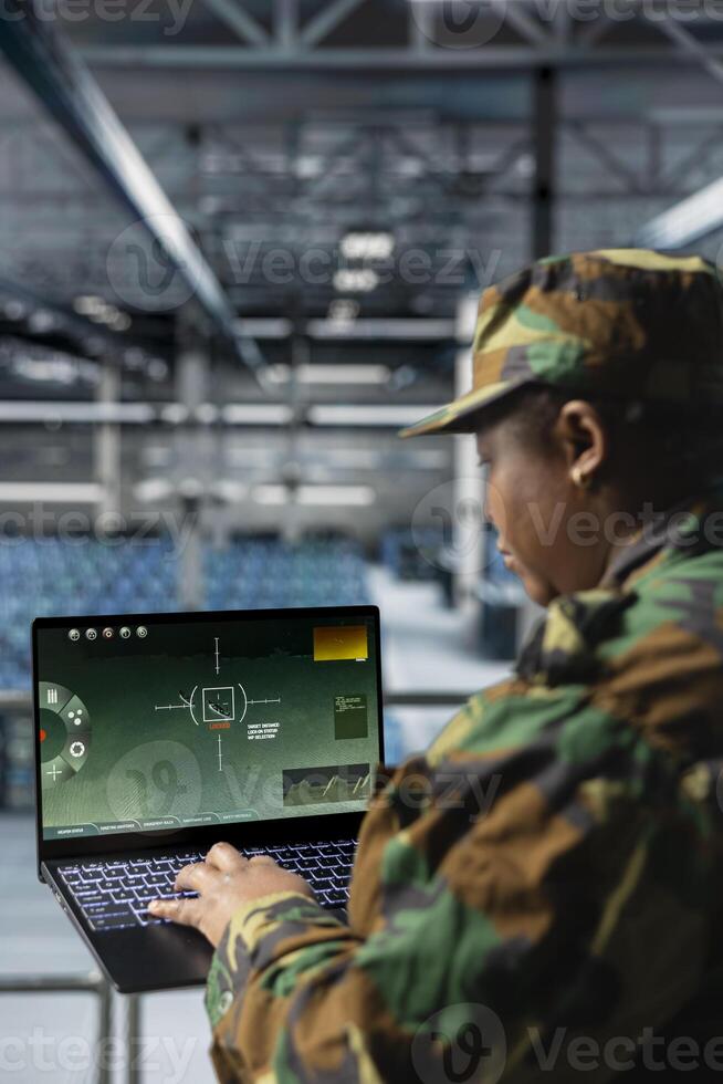 Close up of army expert in data center scanning terrain in real time using military satellite control. Military units wearing uniform in server farm managing orbital telemetry on laptop photo