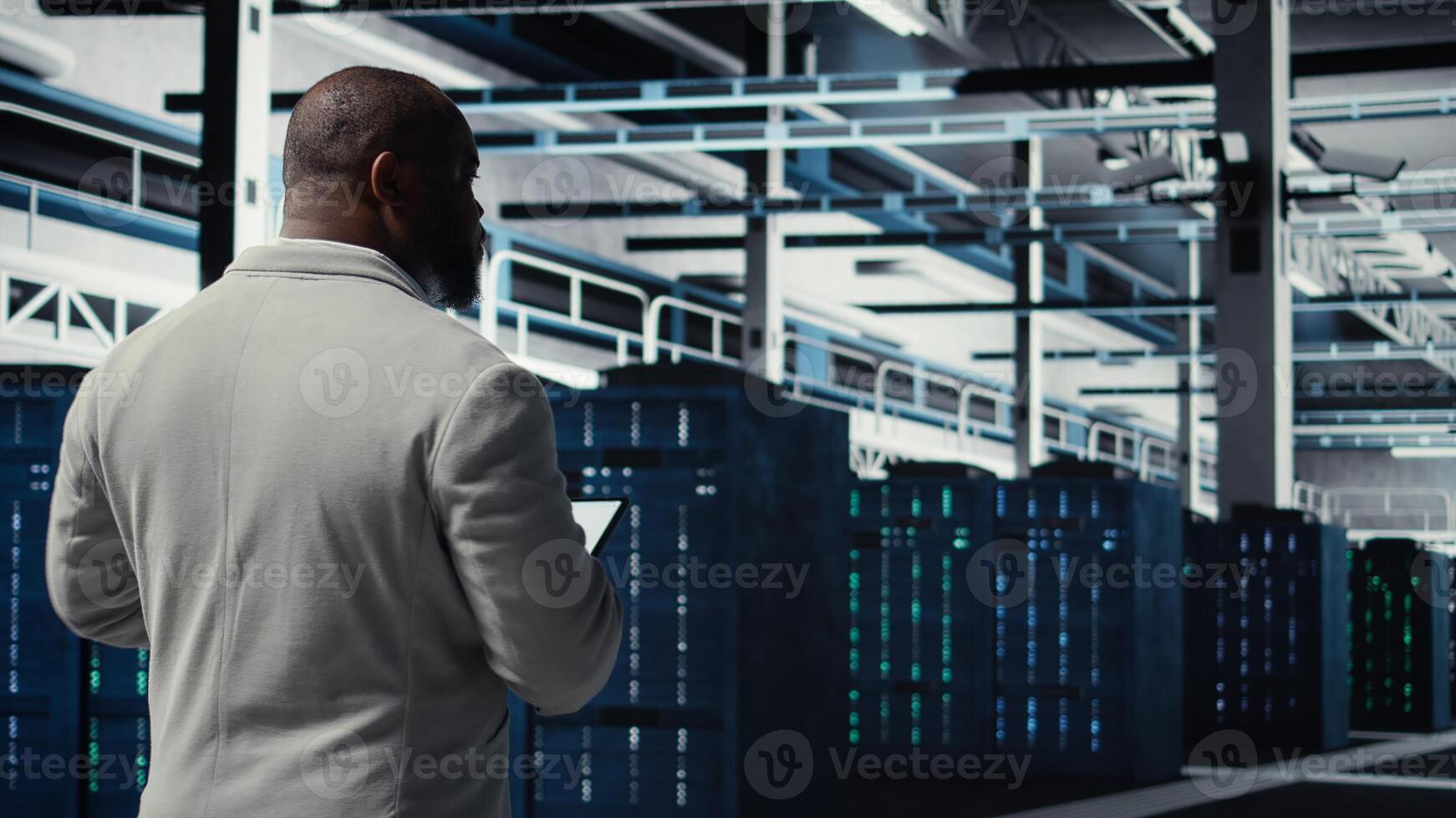 Data center system administrator checking infrastructure diagnostics using tablet screen. IT specialist walking in high tech server room, examining data charts during system audit, camera A photo