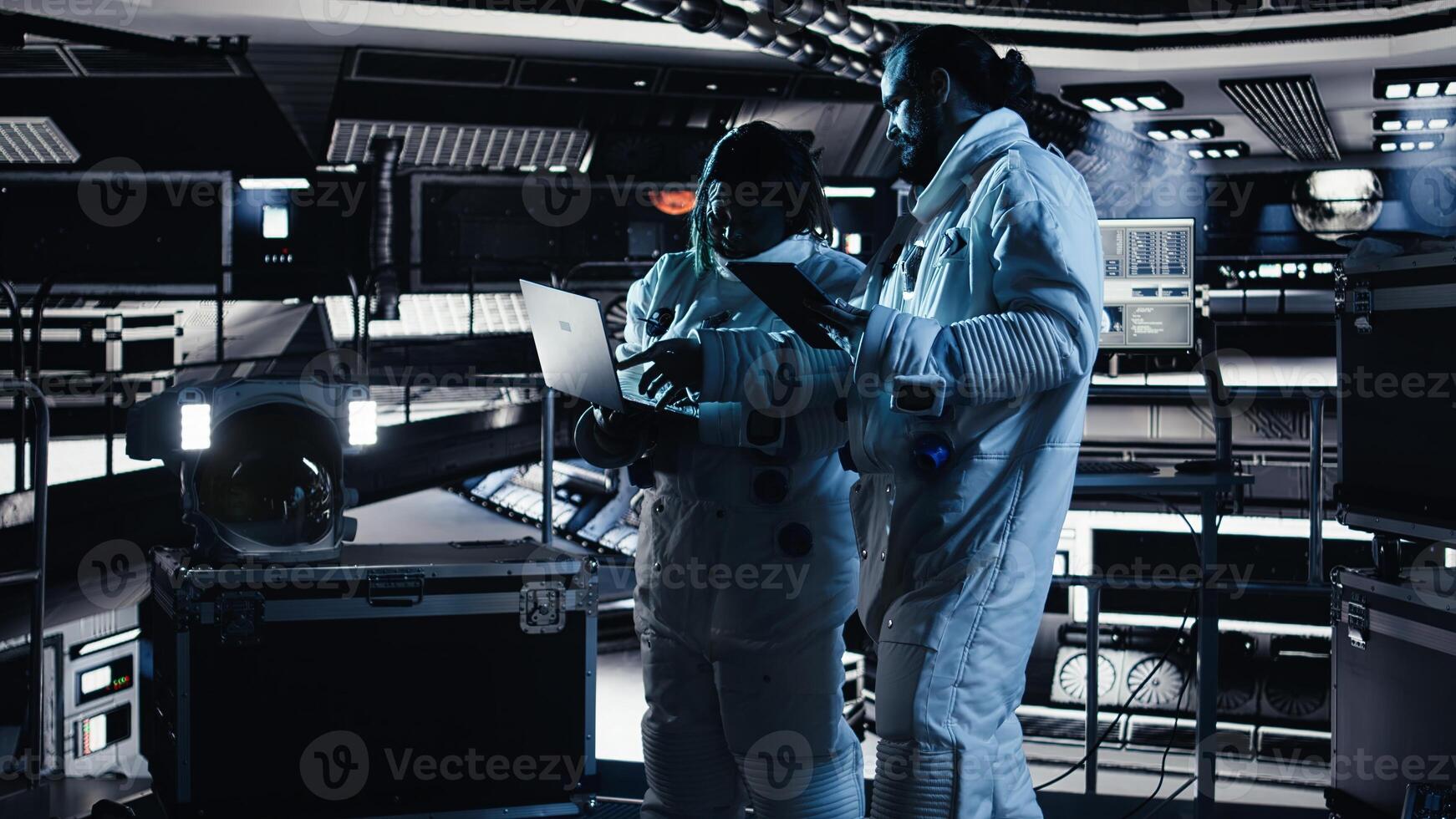 Astronaut looks at interface showing orbital path, chatting with colleague during space mission. Teamworking cosmonauts troubleshooting hardware during mankind survival expedition photo