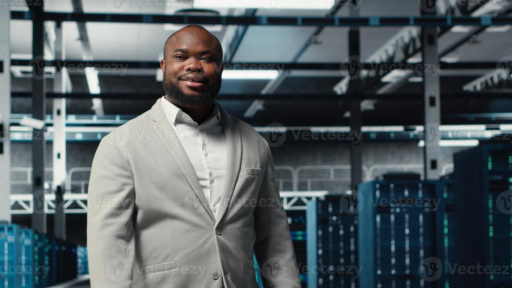 Smiling engineer walking in data center, checking hardware for system stability. Happy employee overseeing server farm, configuring infrastructure to optimize performance, camera B photo