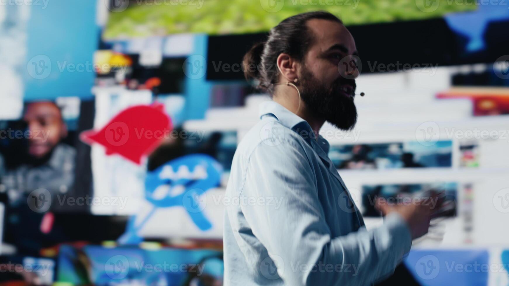 With a hands free microphone, male trend setter hosts a live presentation offering insight for innovation. Speaker discussing with the audience about online entertainment. Camera A. photo