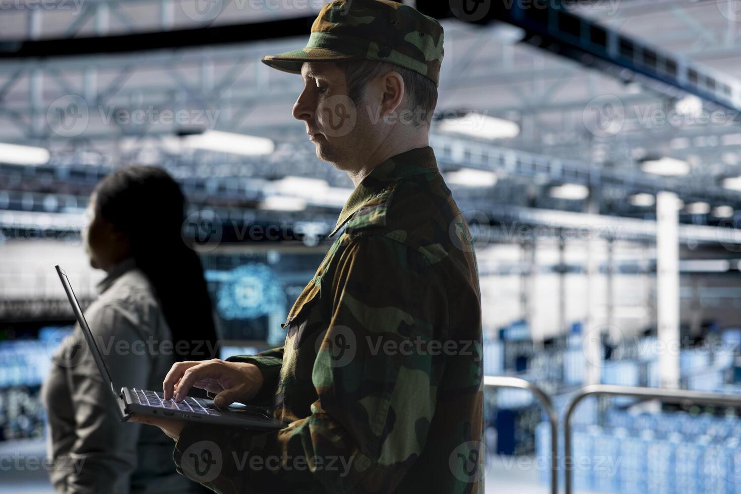 Soldier maintaining secure military networks inside data center facility. Army information technology professional in server room monitoring classified systems using laptop photo