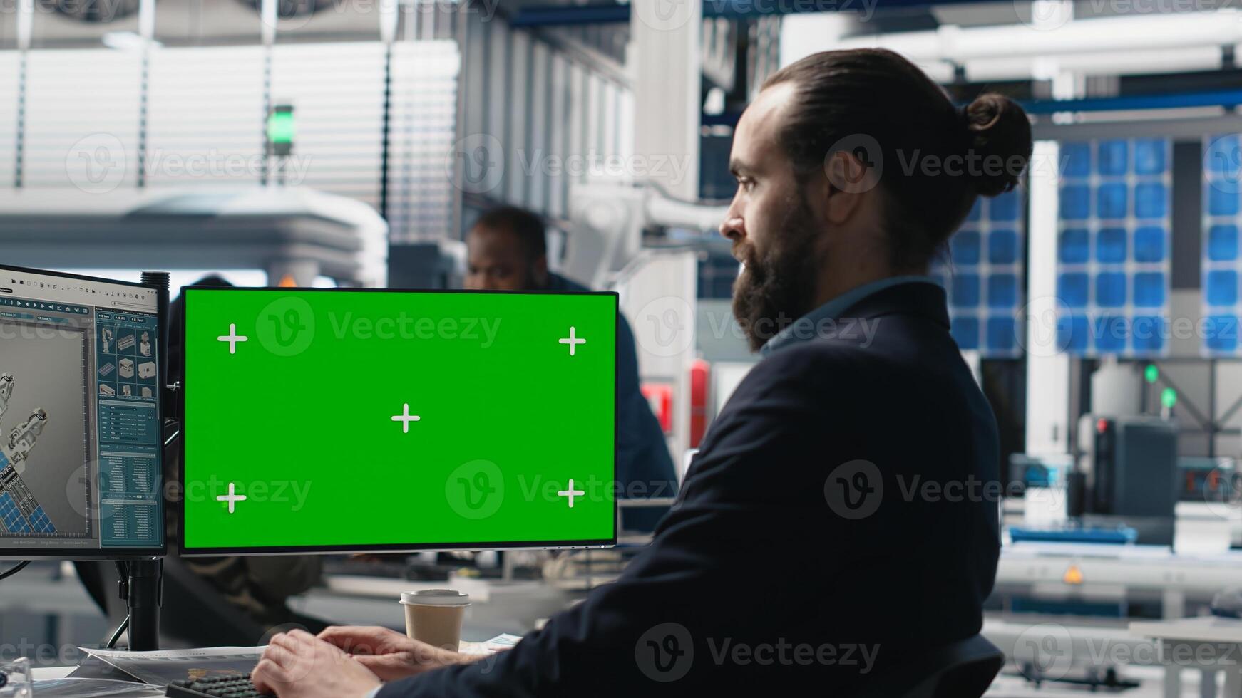 Young business specialist uses computer with green screen and production metrics, overseeing the industrial operations and high tech equipment. Master engineer works on sustainability. Camera B. photo