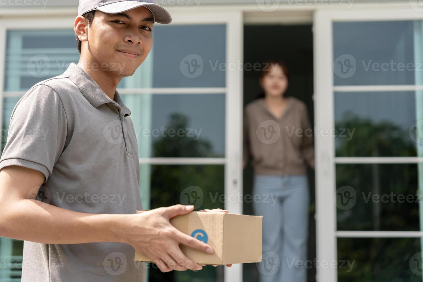 Happy smiling woman receives boxes parcel from courier in front house. Delivery man send deliver express. online shopping, paper containers, takeaway, postman, service, packages. photo