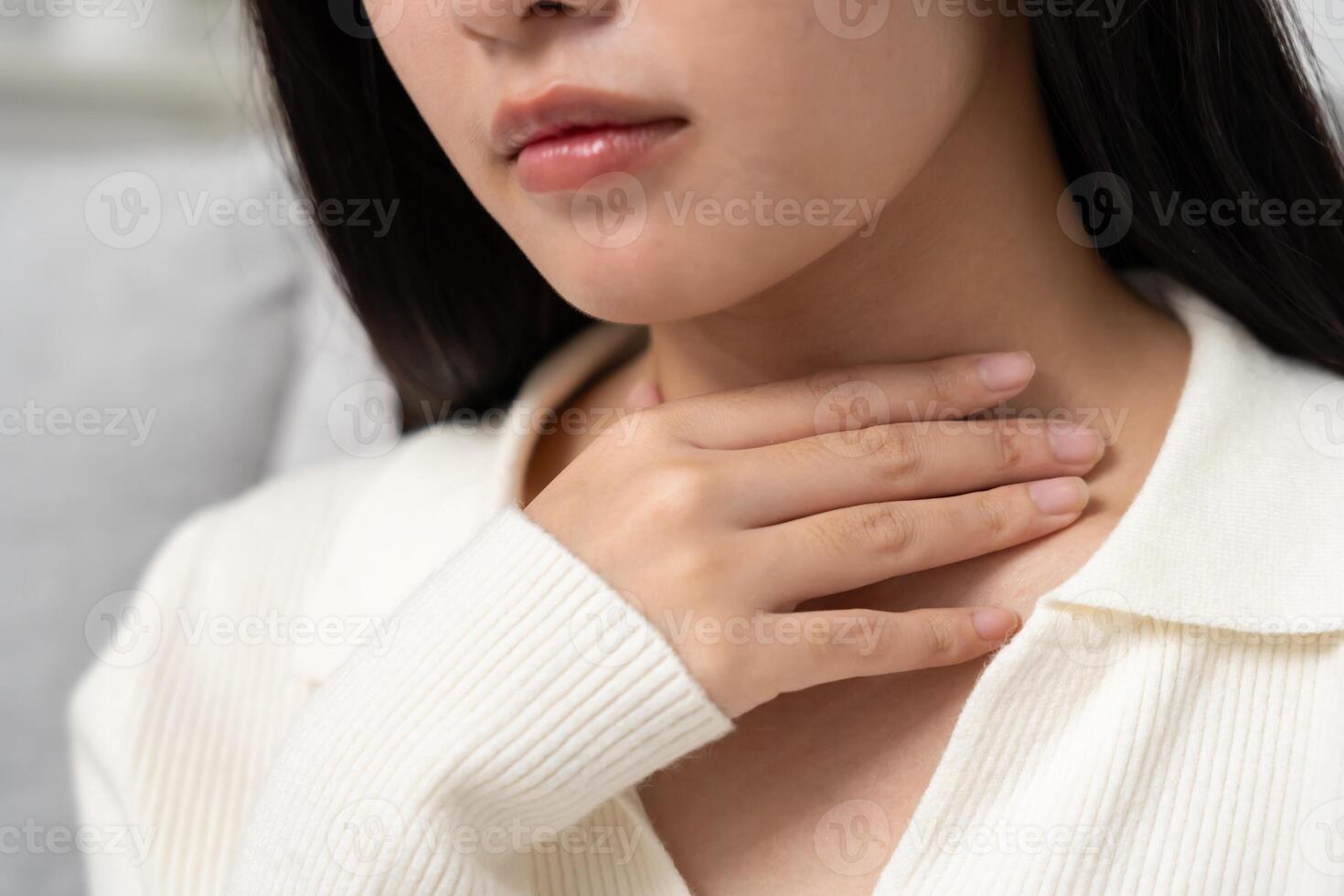 Asian woman put on neck due to a sore throat. female tonsillitis causes a inflammation. treated by taking water, taking antibiotics, consult a doctor, virus, corona virus, Influenza, flu. photo