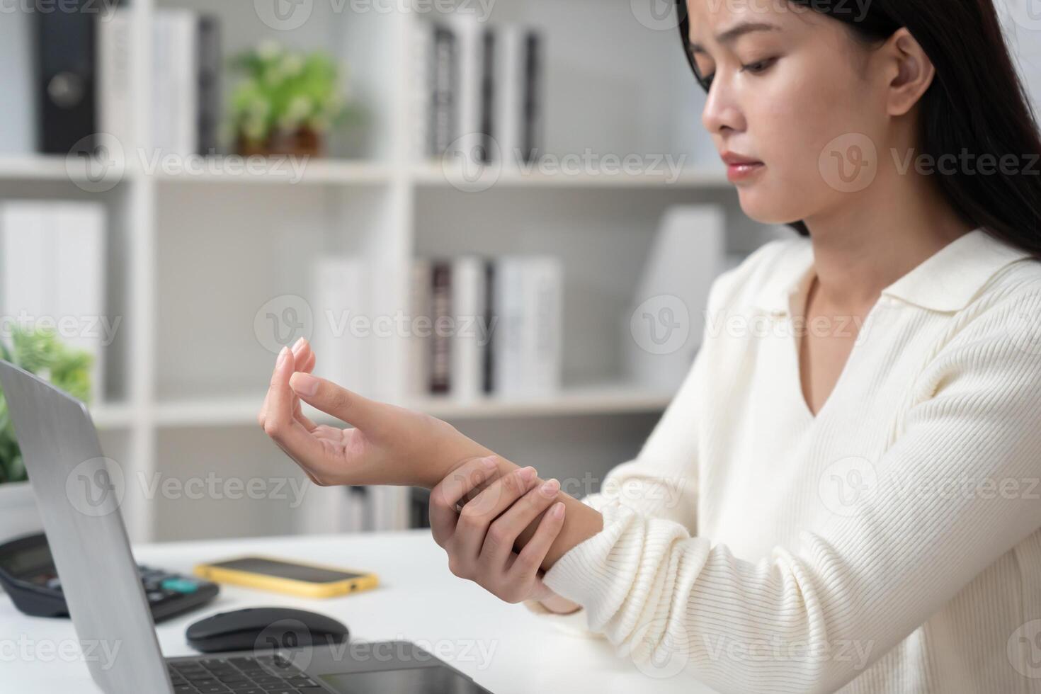 young woman working in office with a carpal tunnel syndrome or wrist joint inflammation, hand muscle inflammation from office syndrome , hand muscle pain from working. photo