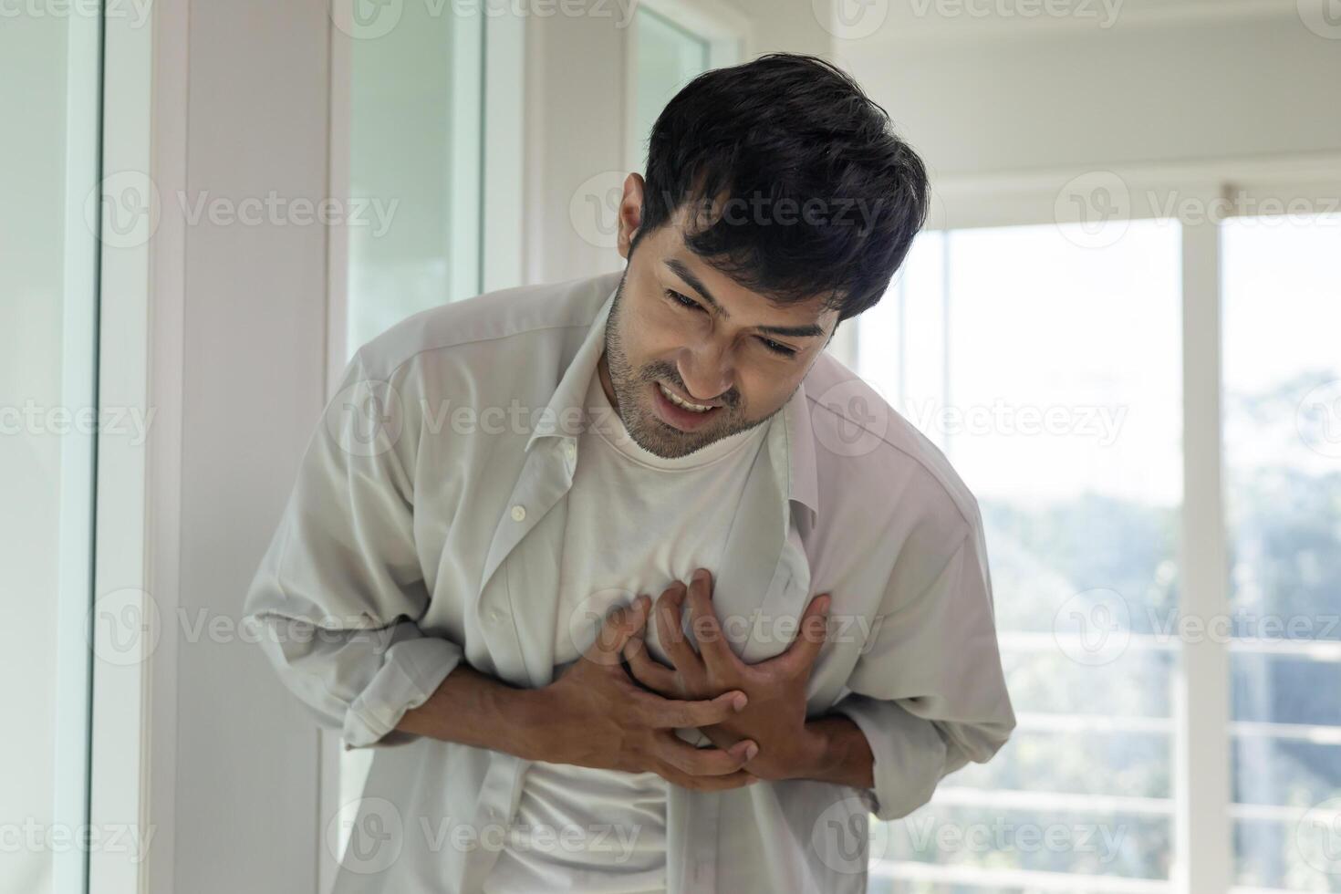 hand hold chest with heart attack symptoms, asian man have chest pain caused by heart disease, leak, dilatation, enlarged coronary heart, press on the chest with a painful expression., photo
