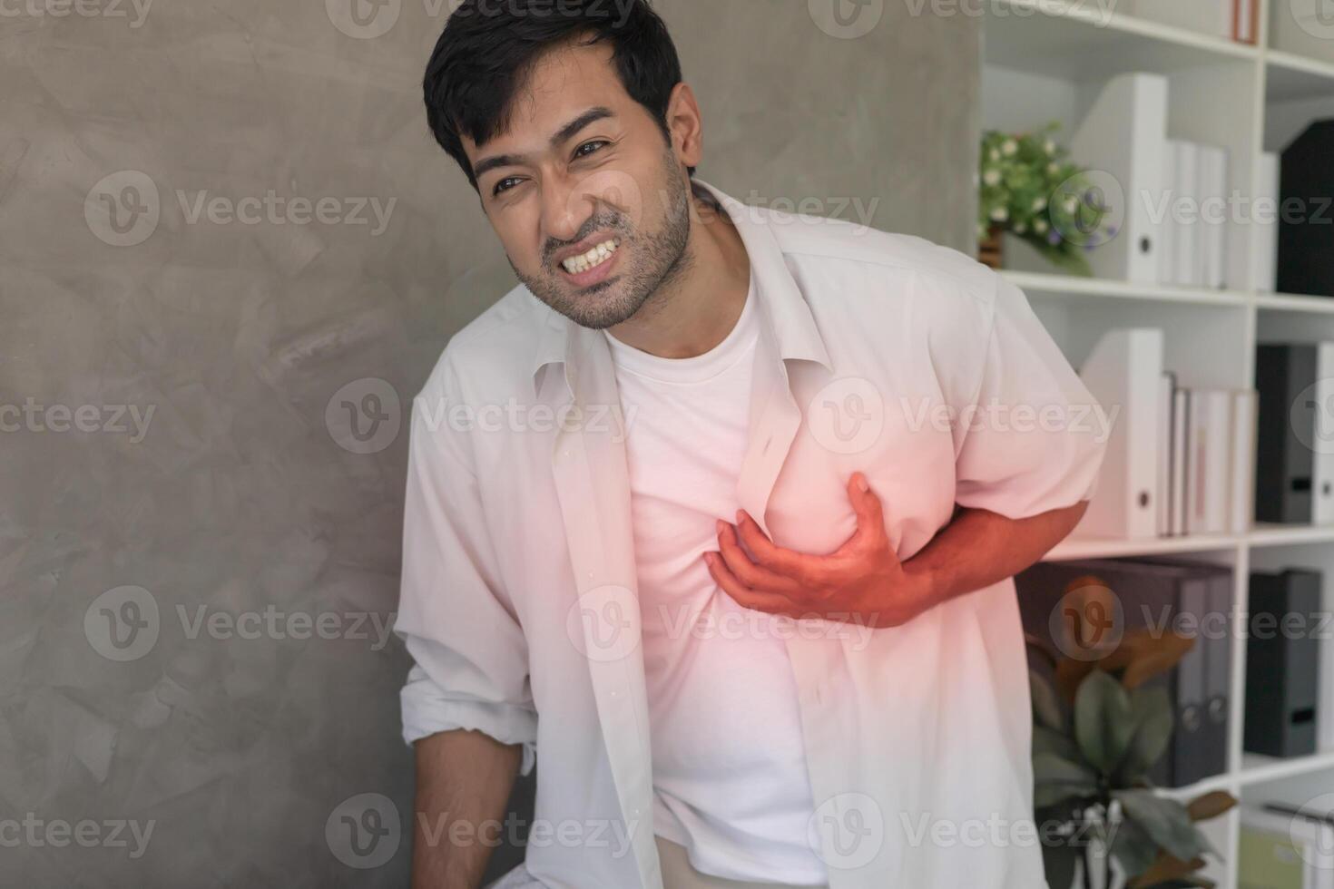 hand hold chest heart attack symptoms, asian man working hard have chest pain caused by heart disease, leak, dilatation, enlarged coronary heart, press on the chest with a painful expression photo