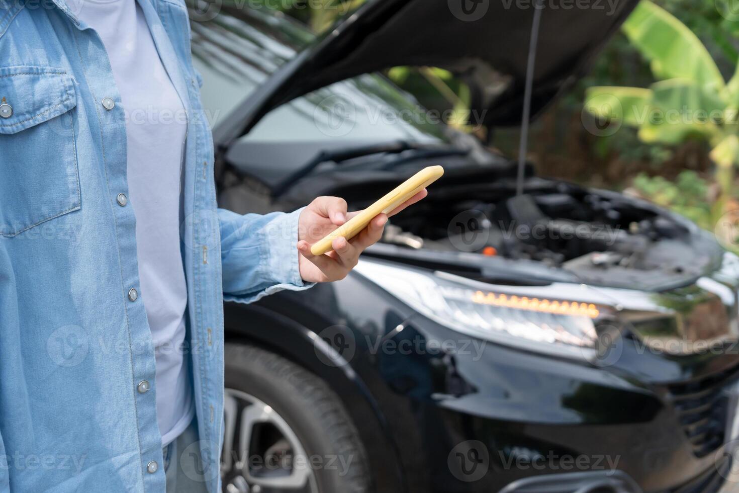 breakdown, broken car, repair. Woman uses mobile phone check insurance premiums through application due to car accident . Find garage to get car fixed during country tour, waiting for help. photo