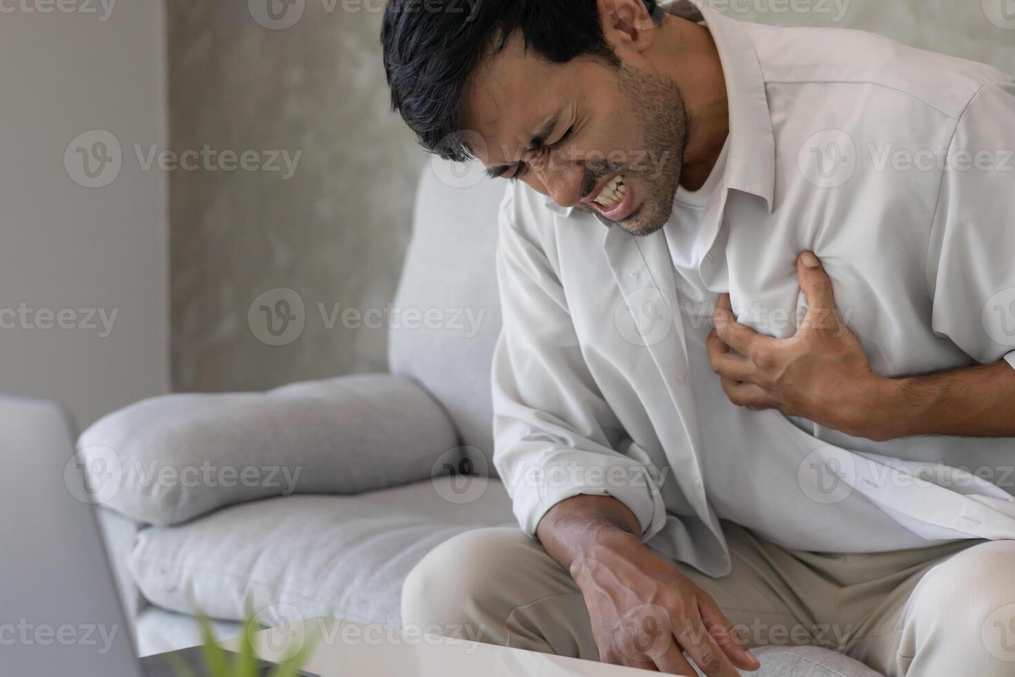 hand hold chest with heart attack symptoms, man working hard have chest pain caused by heart disease, leak, dilatation, enlarged coronary heart, press on the chest with a painful expression. photo
