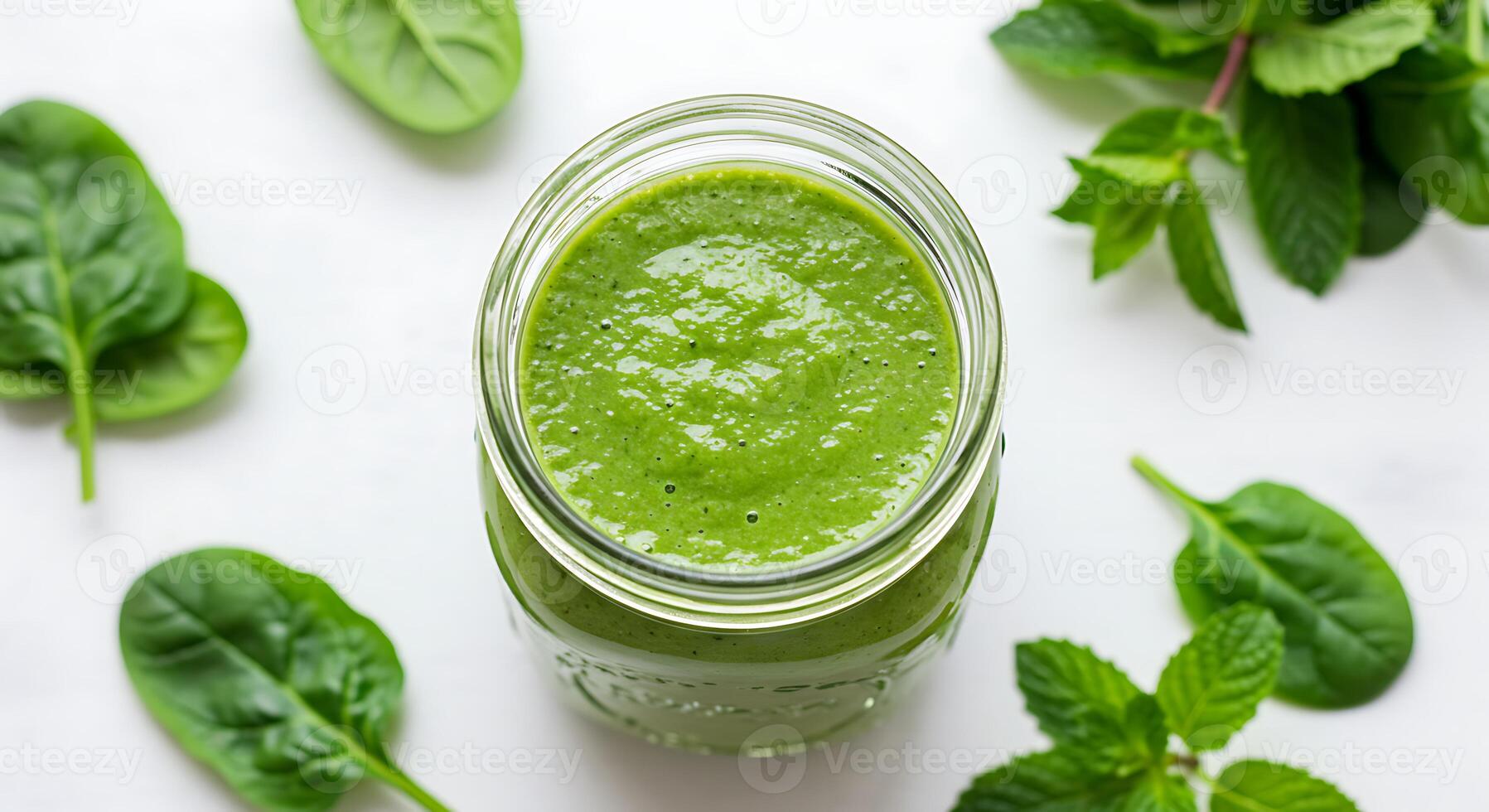 Fresh Green Smoothie in Glass Jar Surrounded by Spinach and Mint Leaves photo