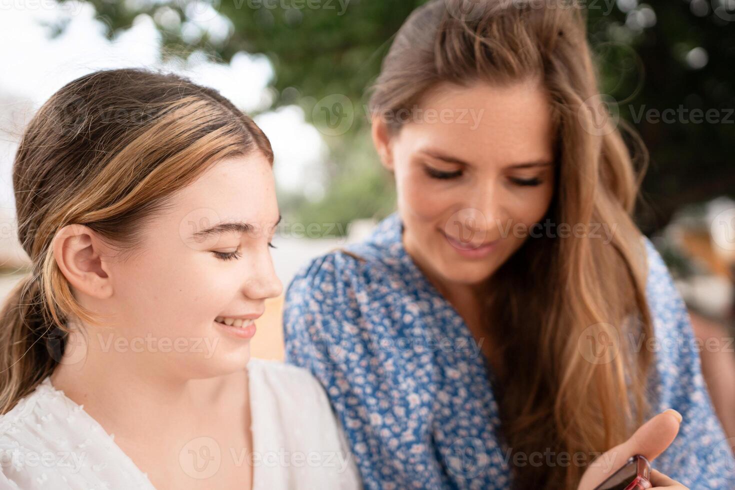 Women Smartphone Outdoors Sharing Two women share smartphone outdoors, daytime casual connection, sharing information or photos. photo