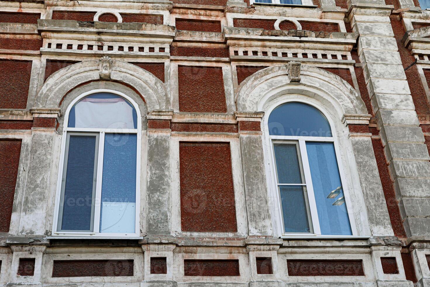 Architectural detail of vintage building featuring arched windows and textured brick facade photo