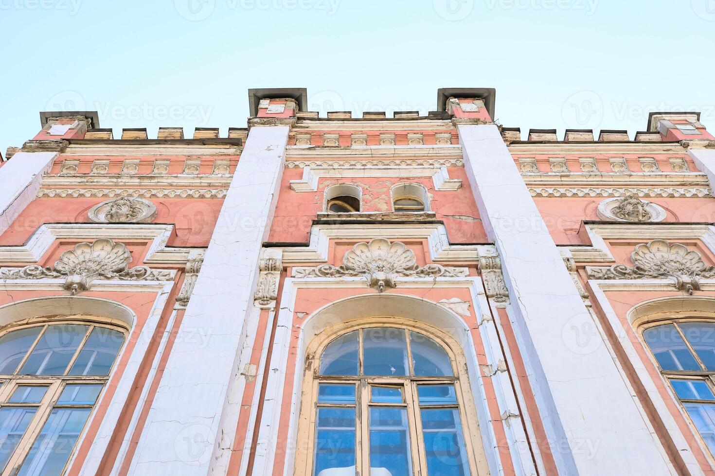 Architectural facade of historic building with ornate details and large windows against clear sky photo