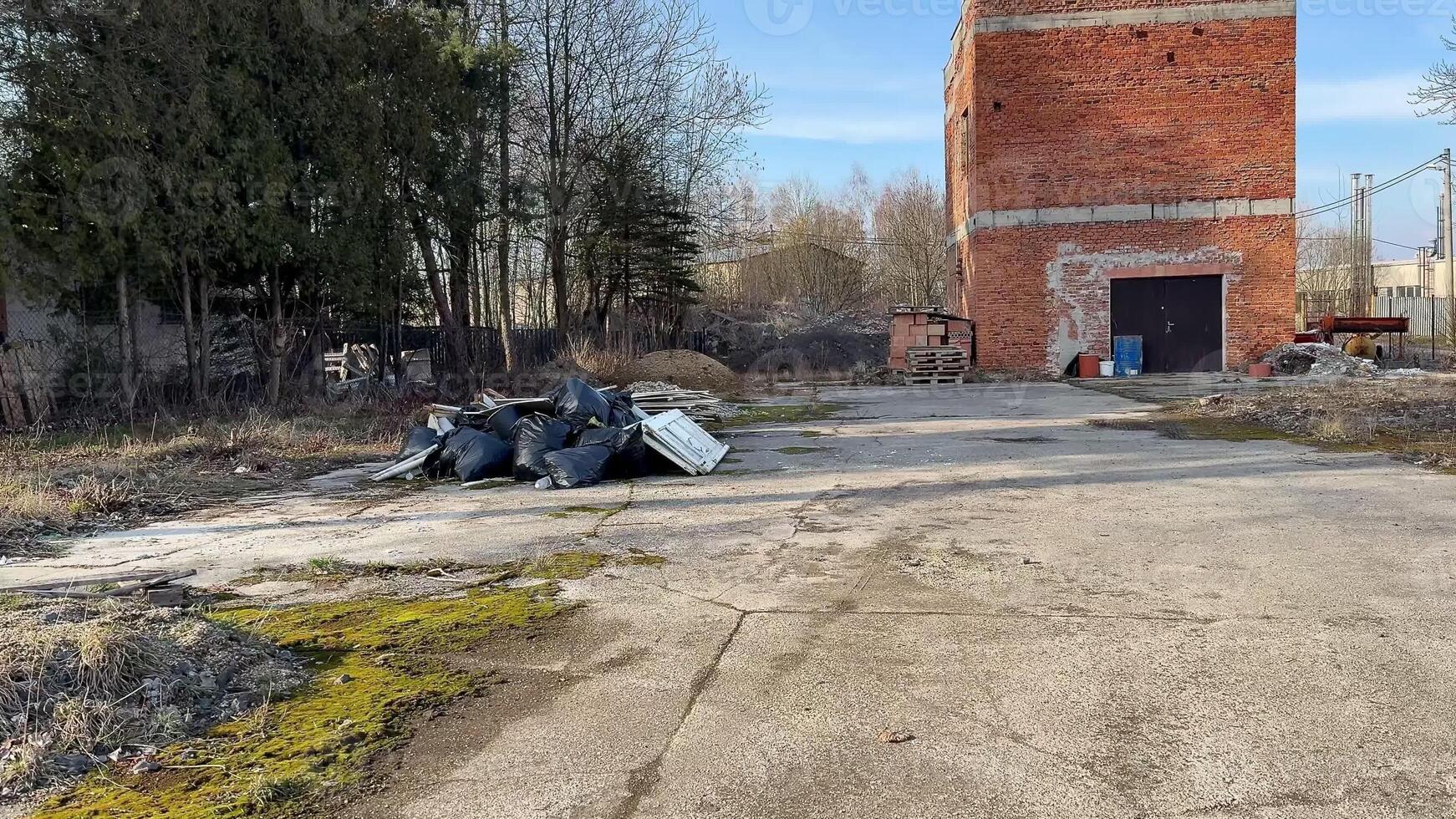 A desolate industrial site featuring a brick building and scattered debris in a neglected environment. photo