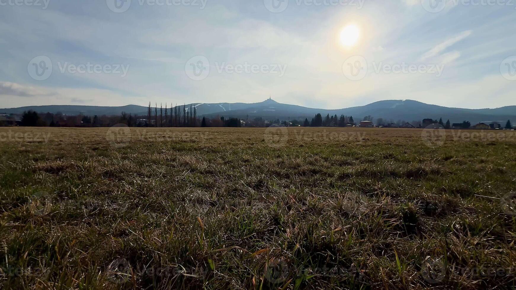 A tranquil view of vast fields with rolling hills and a glowing sun, perfect for nature-themed projects. photo
