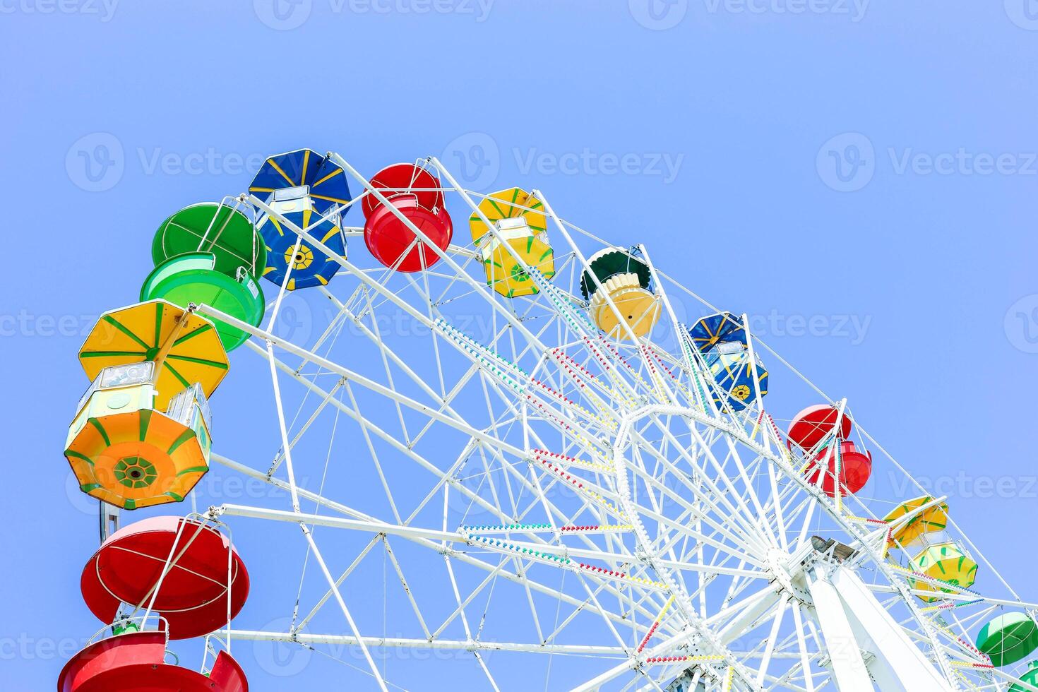 Colorful ferris wheel against a clear blue sky, showcasing vibrant gondolas and structure photo
