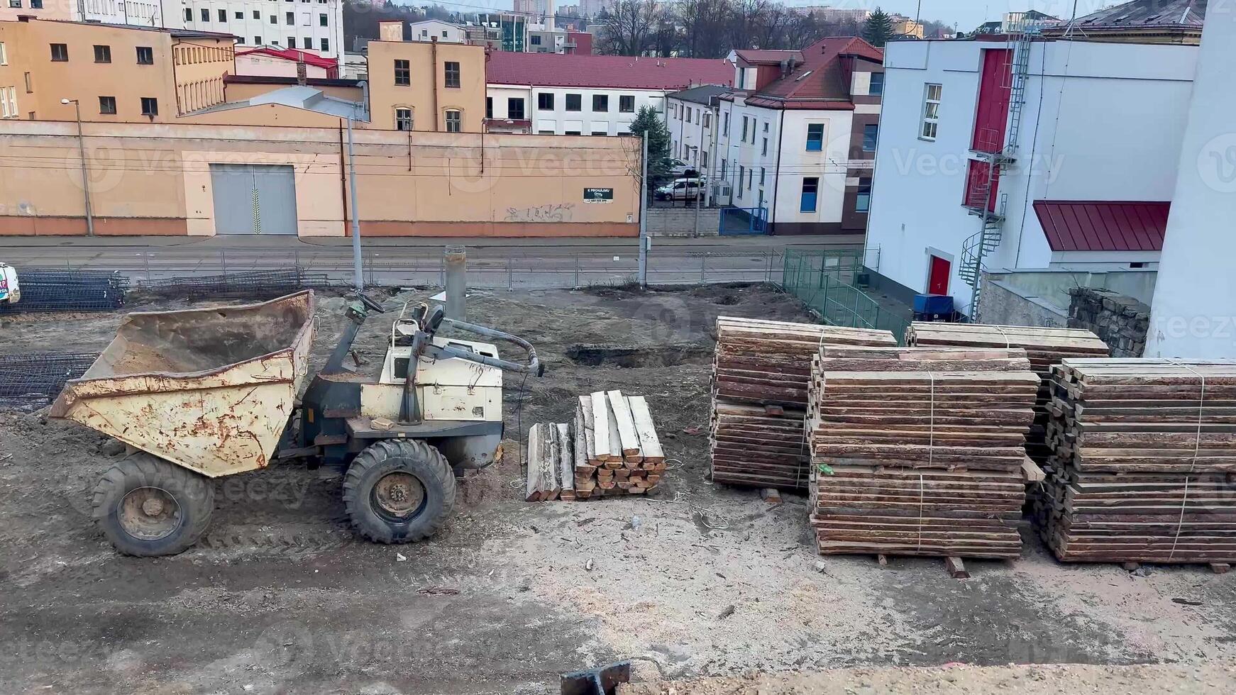 A bustling construction site that prominently features a large dump truck and neatly organized stacks of logs photo