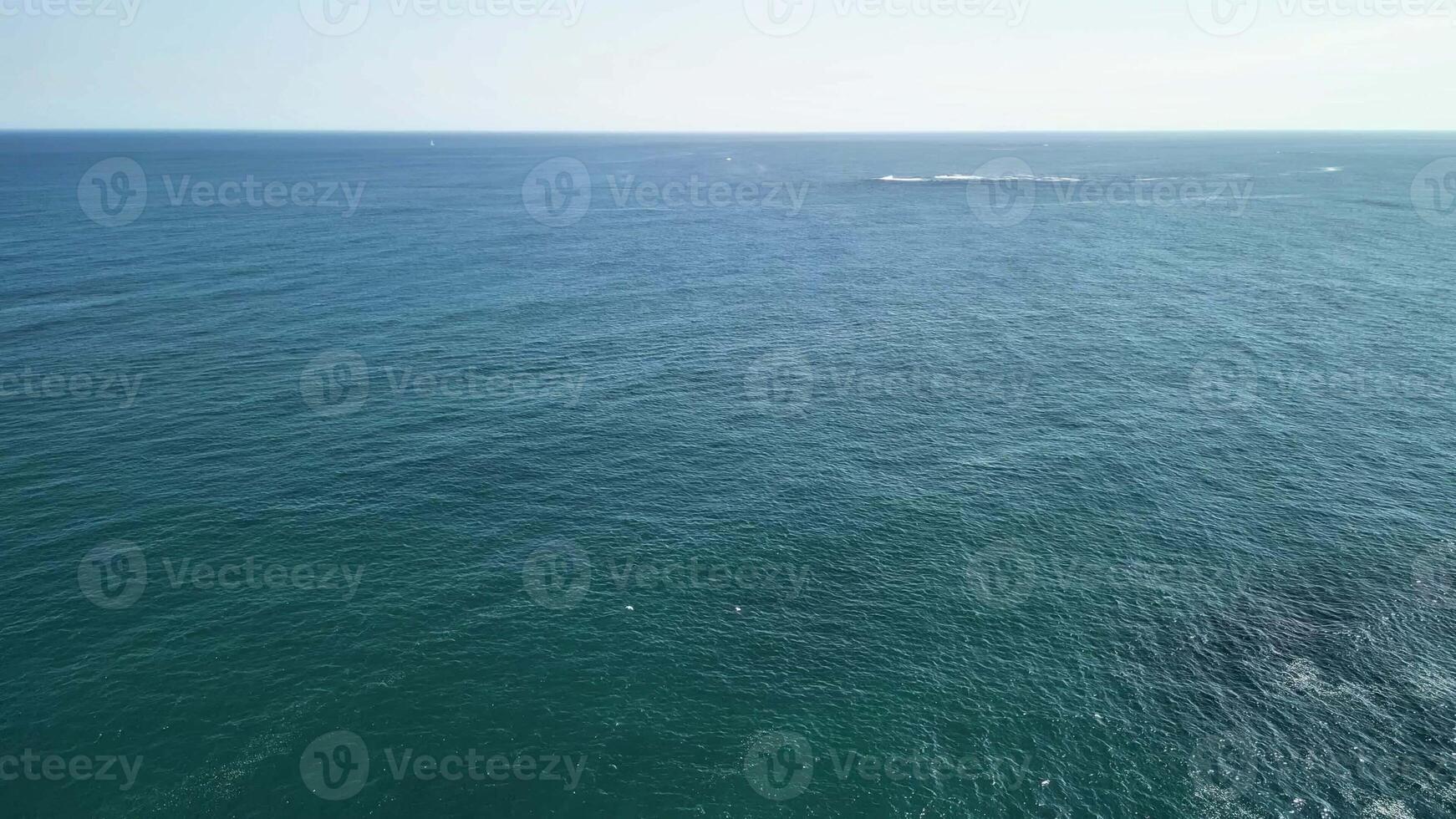Experience stunning aerial footage of clear ocean waters meeting rugged coastal rocks and unique formations photo