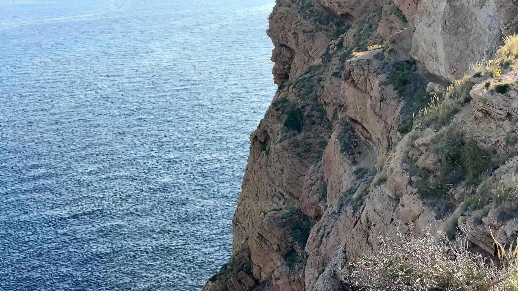 The stunning view showcases rocky cliffs dramatically meeting the calm sea beneath a majestic clear blue sky photo