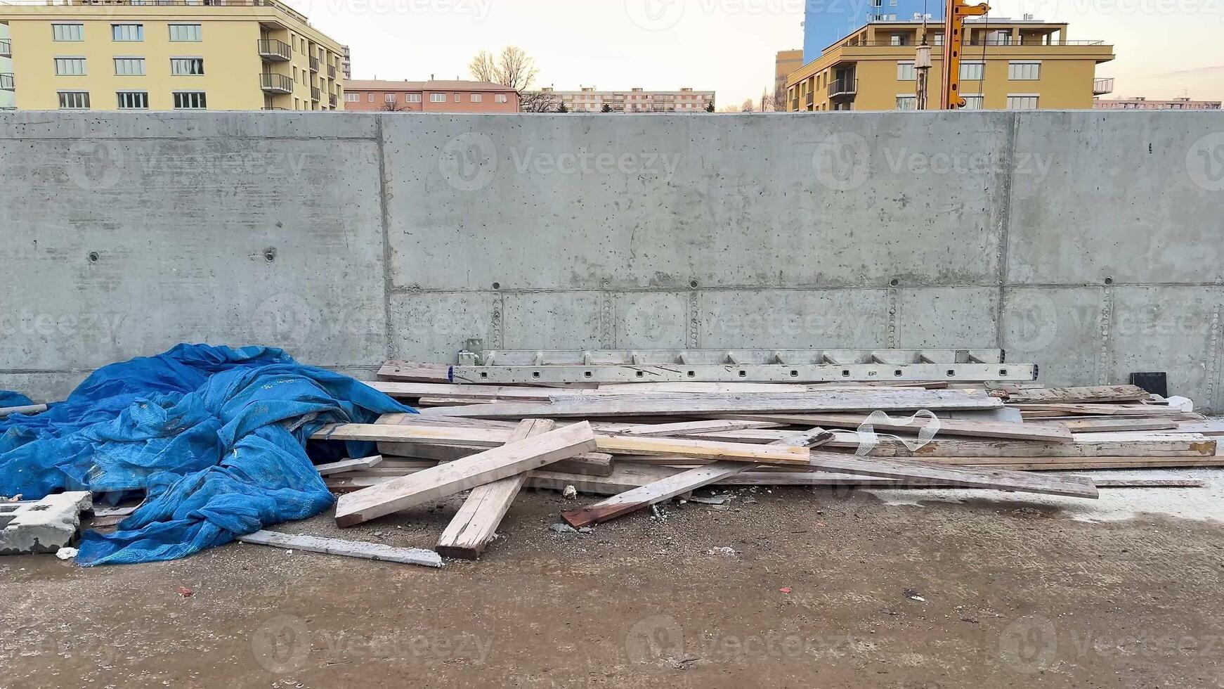 A construction site scene showcasing wooden debris that is partially covered by a blue tarpaulin sheet photo