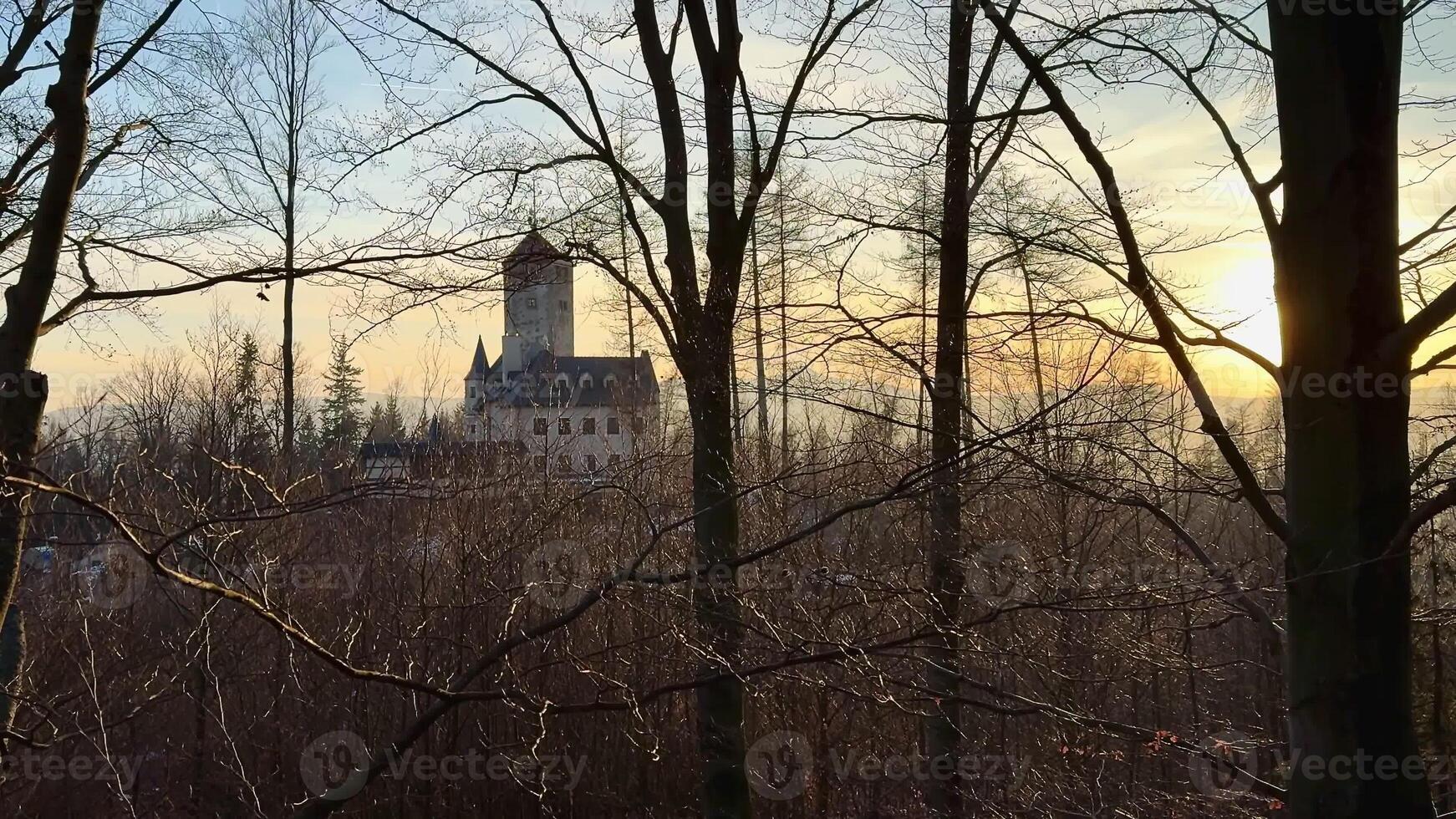 A truly stunning and breathtaking view of a magnificent castle nestled among lush trees during a captivating sunset photo