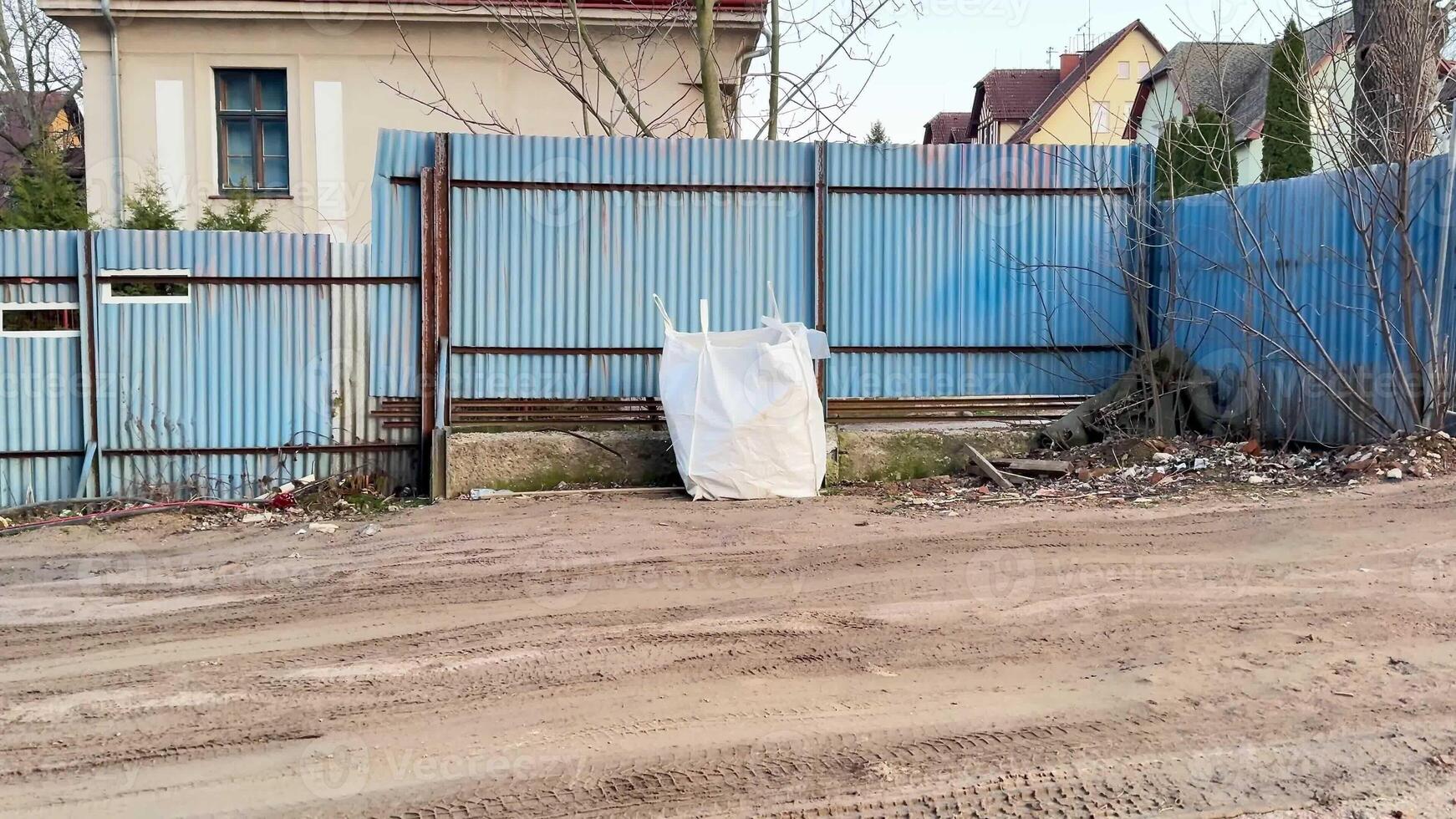 A deserted area showcasing a blue fence and a large pile of trash, which highlights urban decay and neglect photo