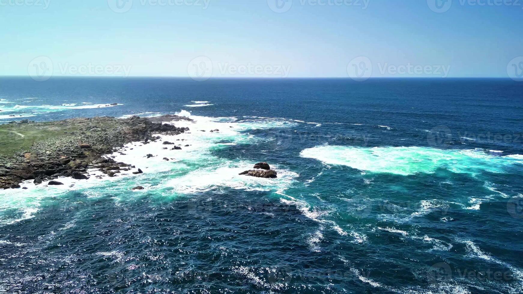 Experience breathtaking and stunning aerial views of rocky coasts and vibrant turquoise waves beneath a serene blue sky photo