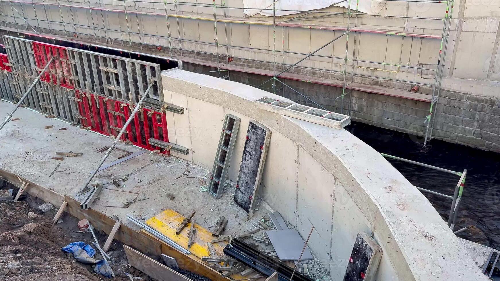 A construction site showcasing a curved concrete structure with scaffolding and construction materials. photo