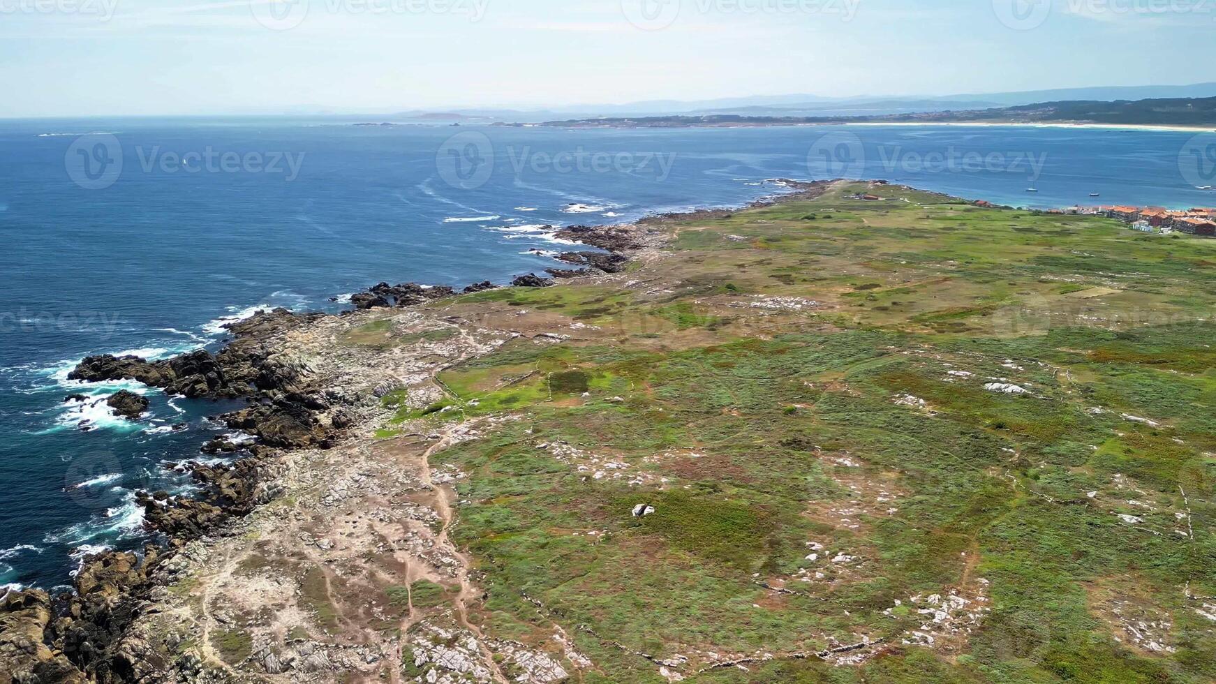Breathtaking aerial views of a rocky coastline adorned with vibrant greenery under the clear blue sky. photo