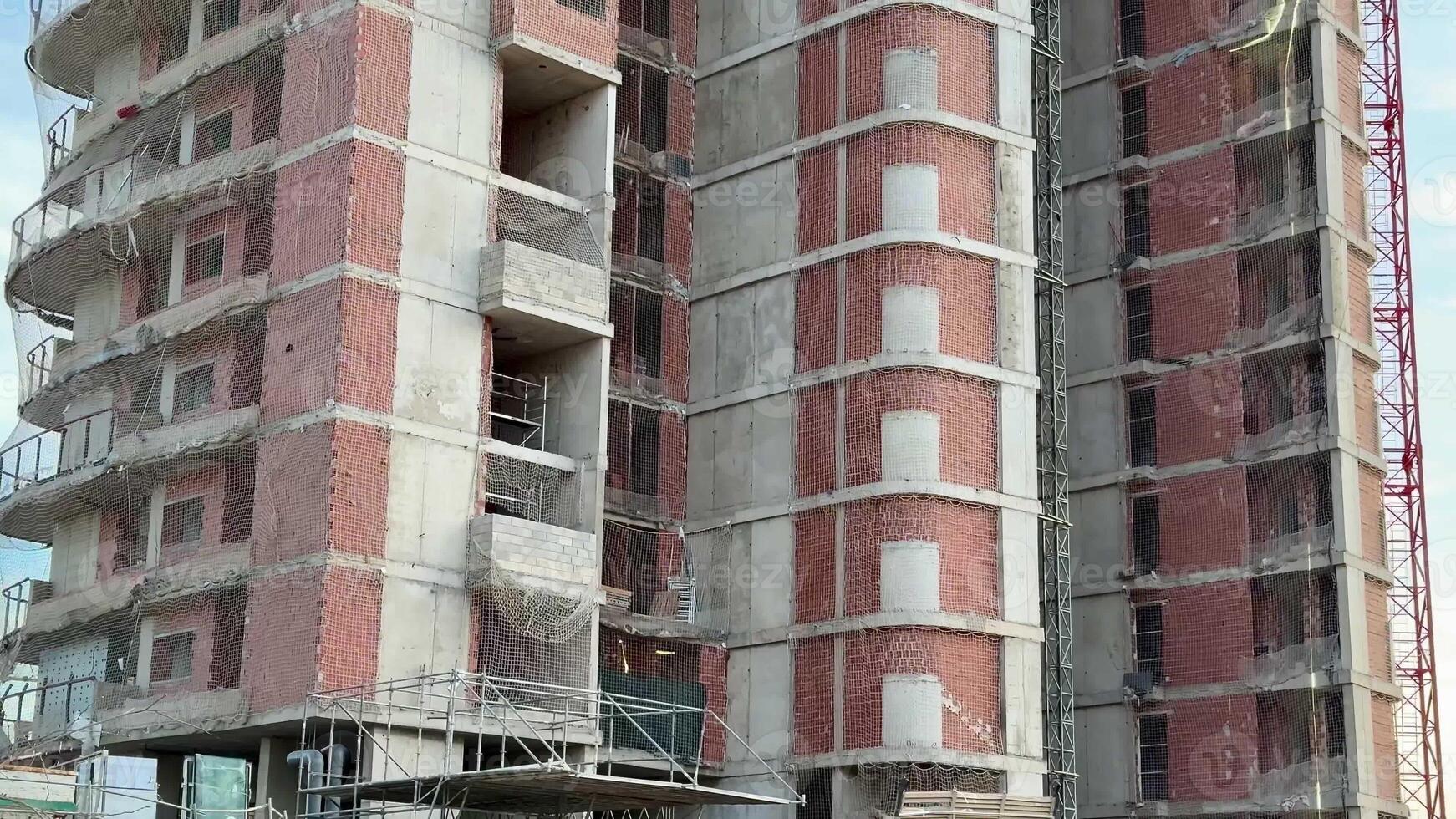 This image shows a multistory building under construction, featuring scaffolding and visible brickwork photo