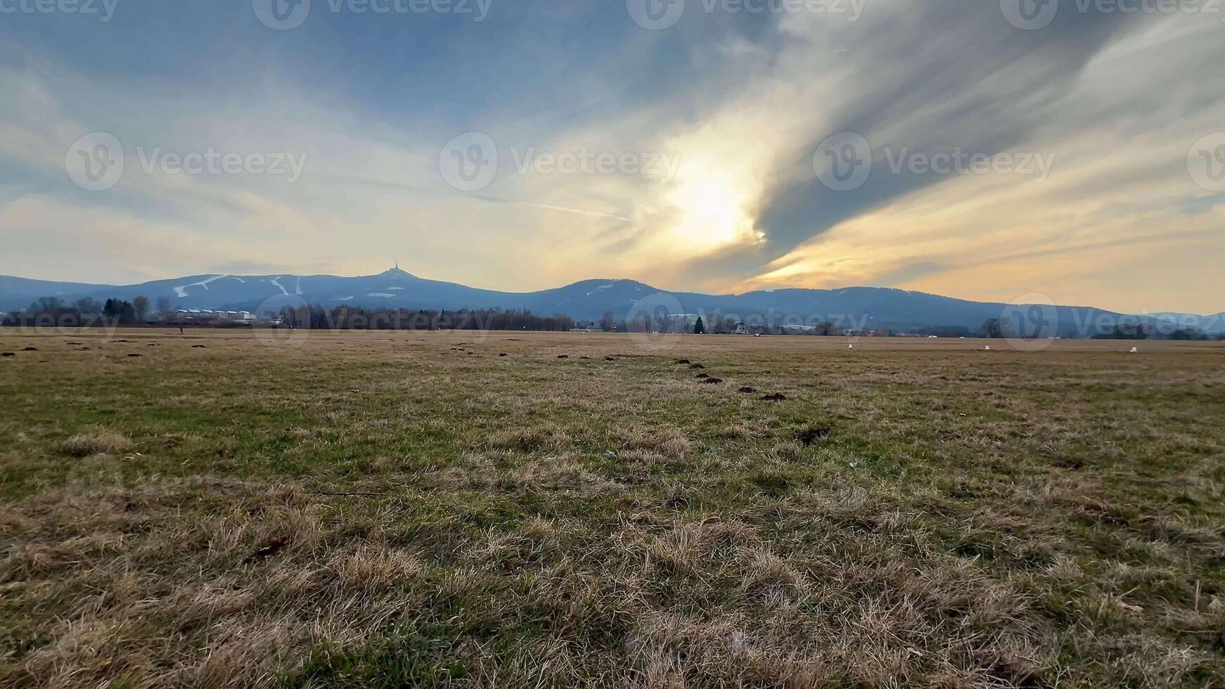 A breathtaking and picturesque view of vast open fields and majestic mountains under a stunning sunset sky to behold photo