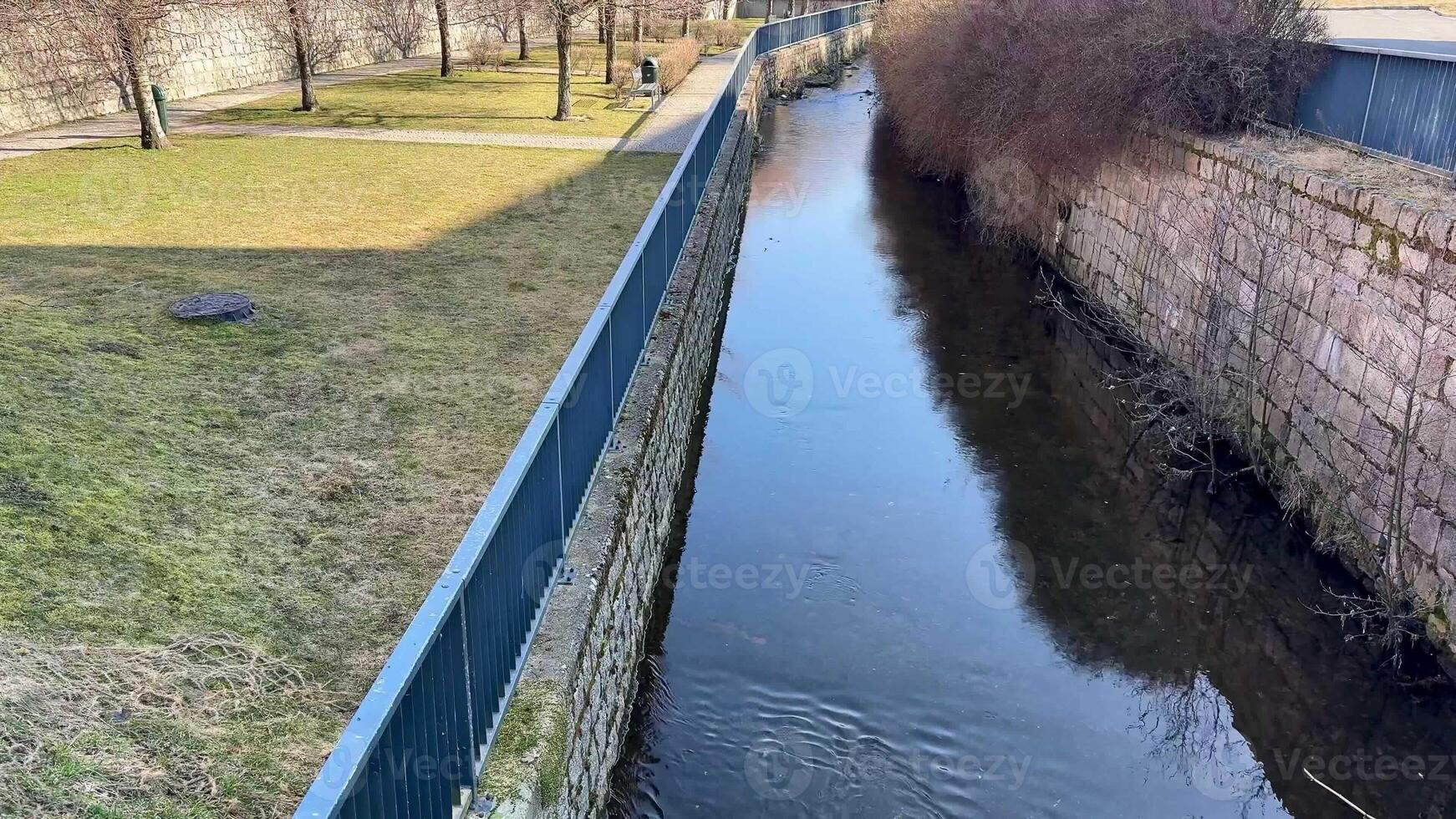 A tranquil stream with lovely fencing, green grass, and vibrant nature, perfect for peaceful reflection and relaxation photo