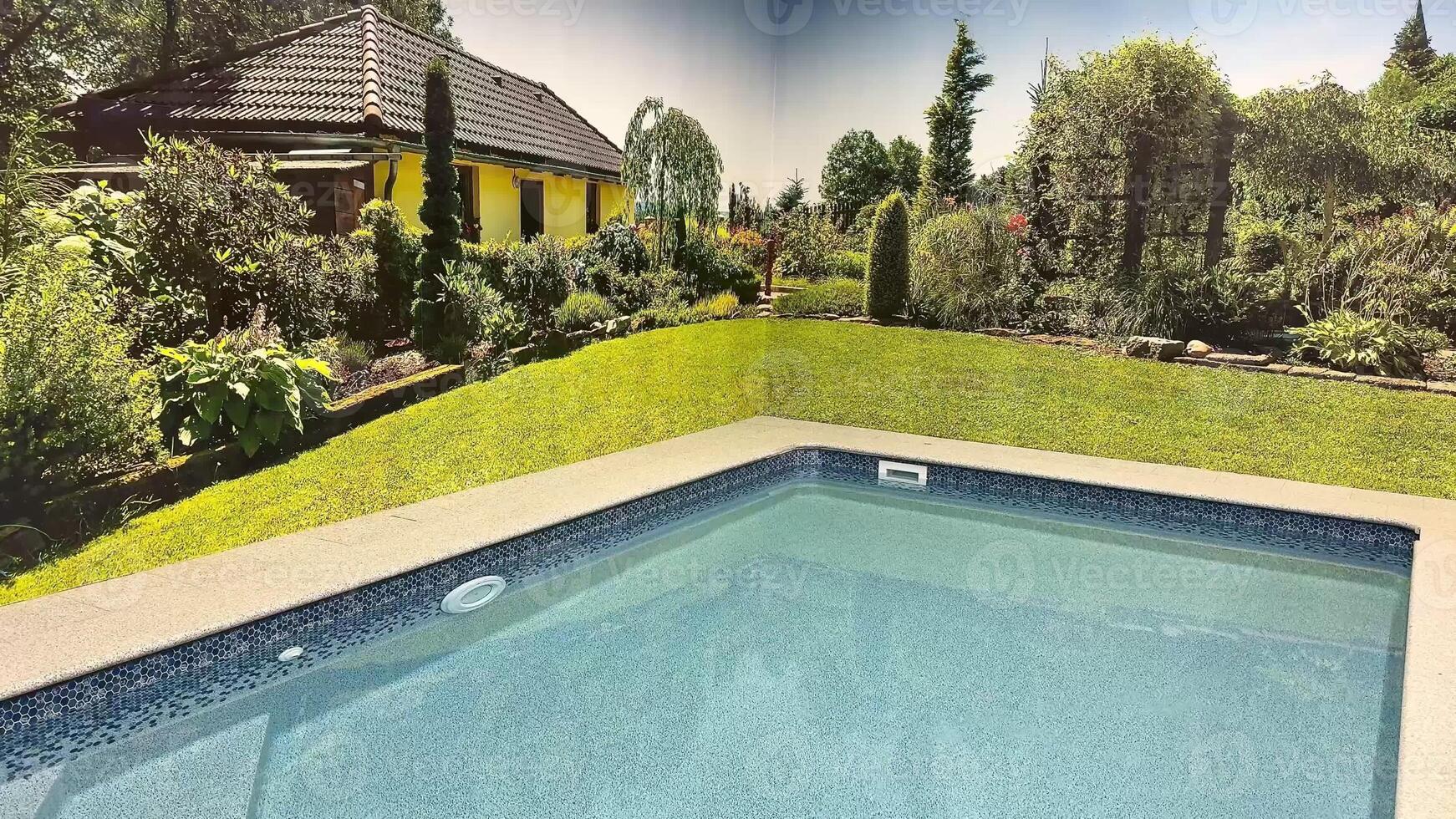 A peaceful and serene poolside view that showcases a vibrant garden as well as a charming house nearby photo