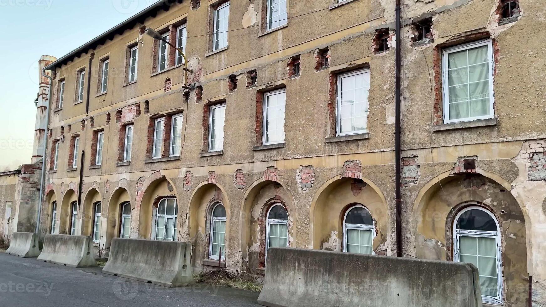 An aged and weathered facade of a longabandoned building showcasing distinctively peeling paint and broken windows photo
